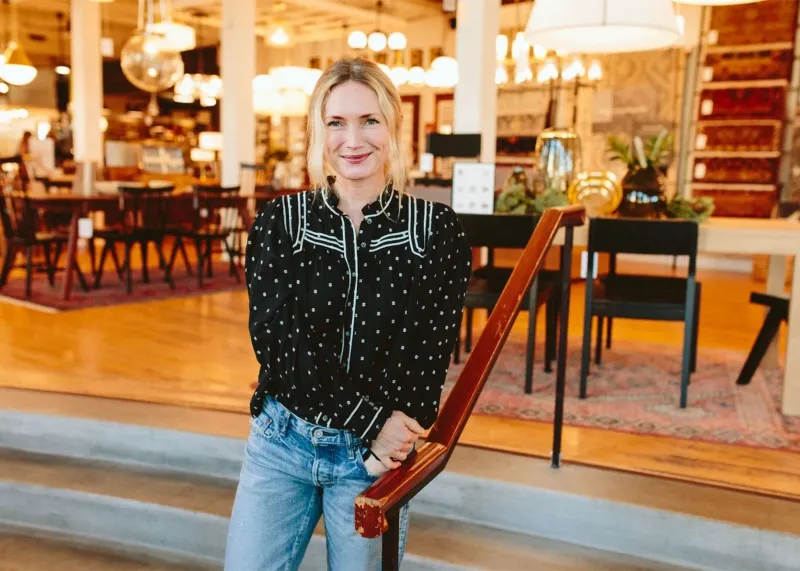 A woman is standing next to a railing in a restaurant.