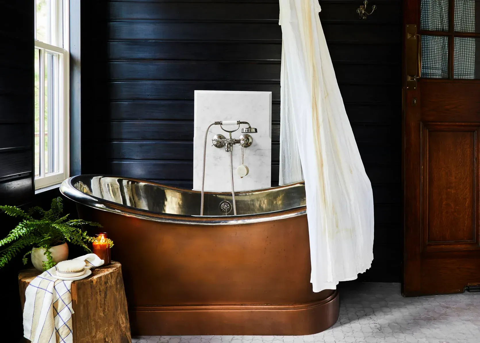 A bathroom with a copper bathtub and a white shower curtain.
