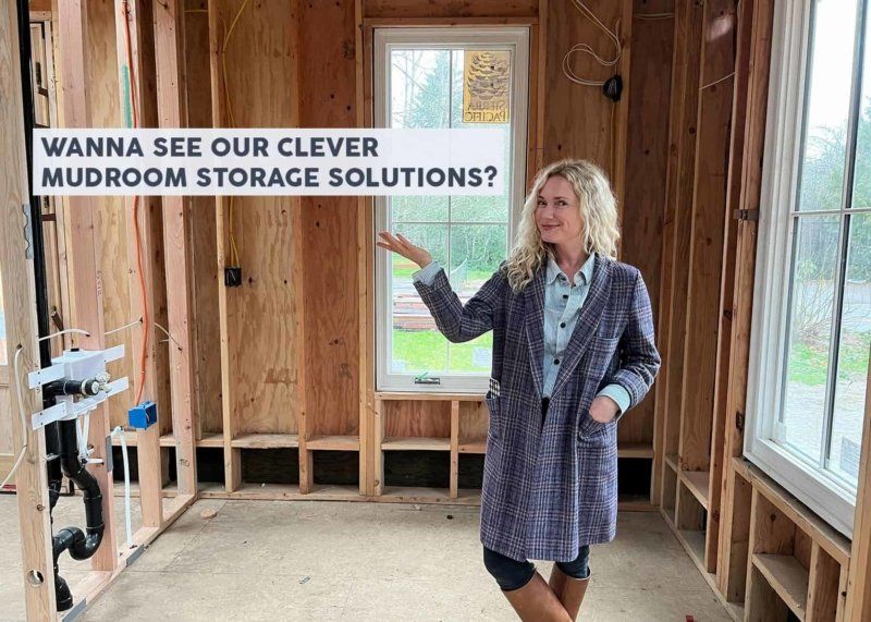 A woman is standing in a room with a sign that says `` wanna see our clever mudroom storage solutions ? ''