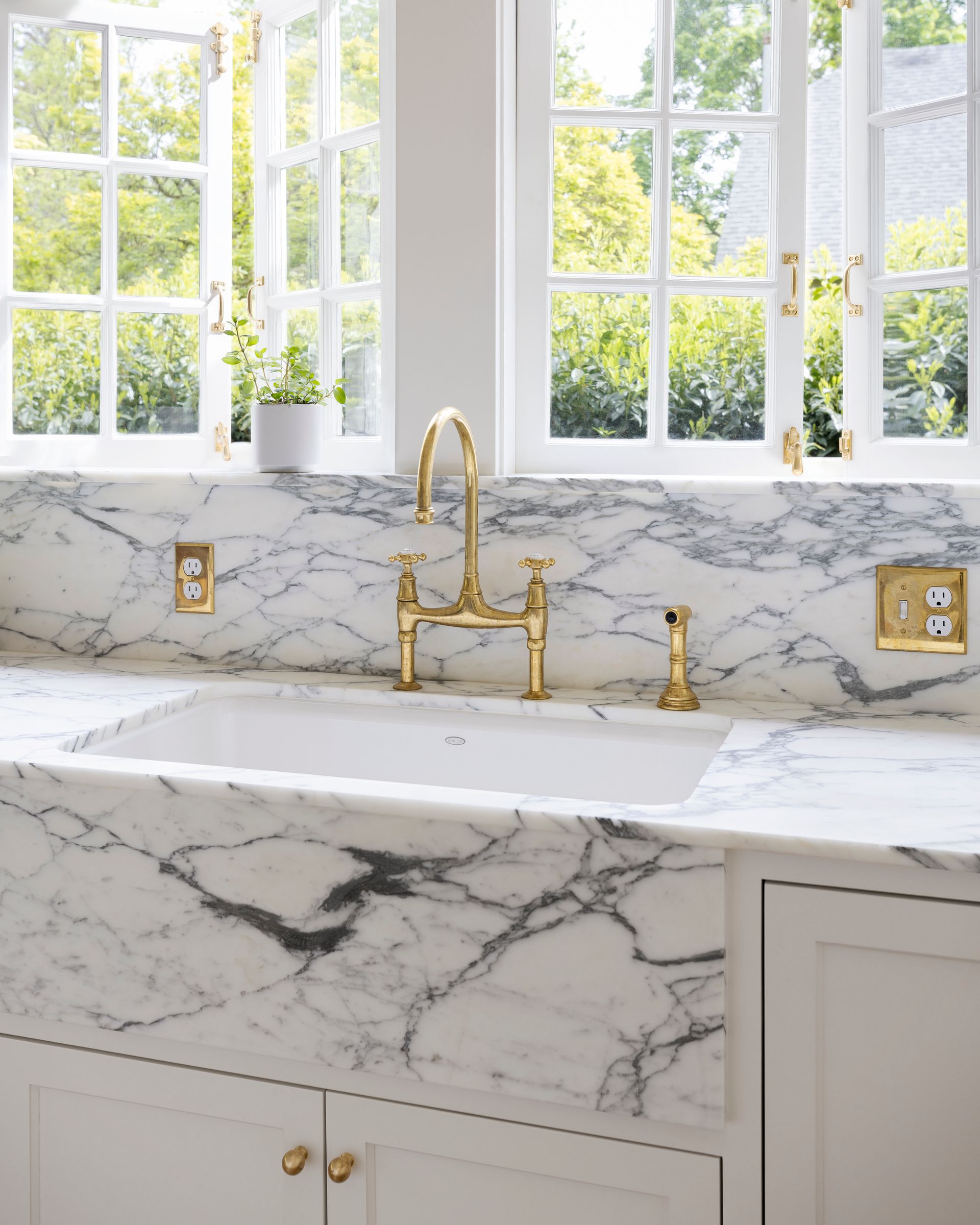 A close up of the beautiful veining in the Arabescato marble at the kitchen sink, under a pair of windows that open to the garden.
