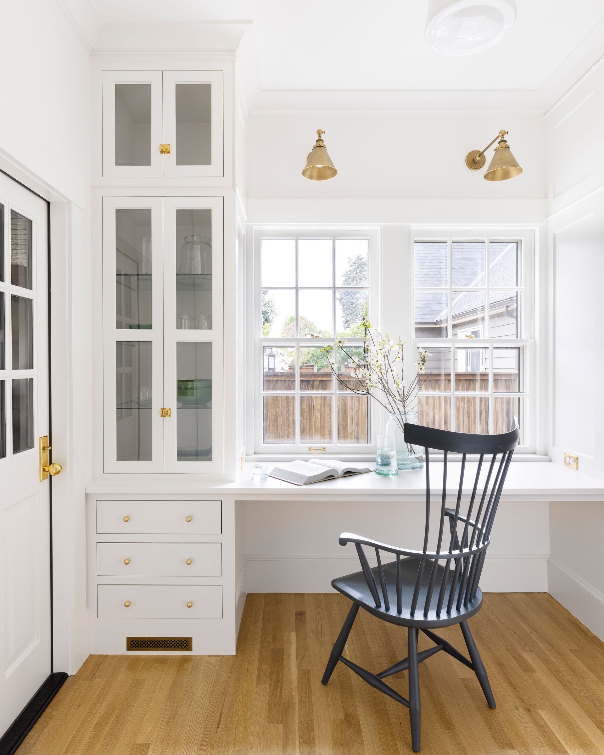 Adjacent to the kitchen is a small office with full height cabinetry and a generous worktop under a pair of windows.