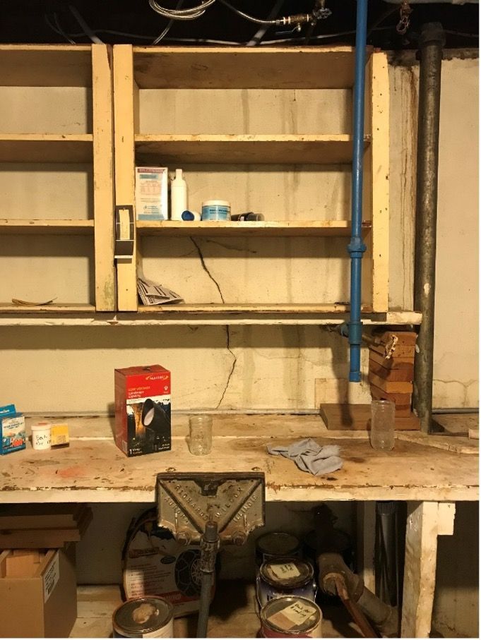 A wooden workbench in a basement with empty shelves.