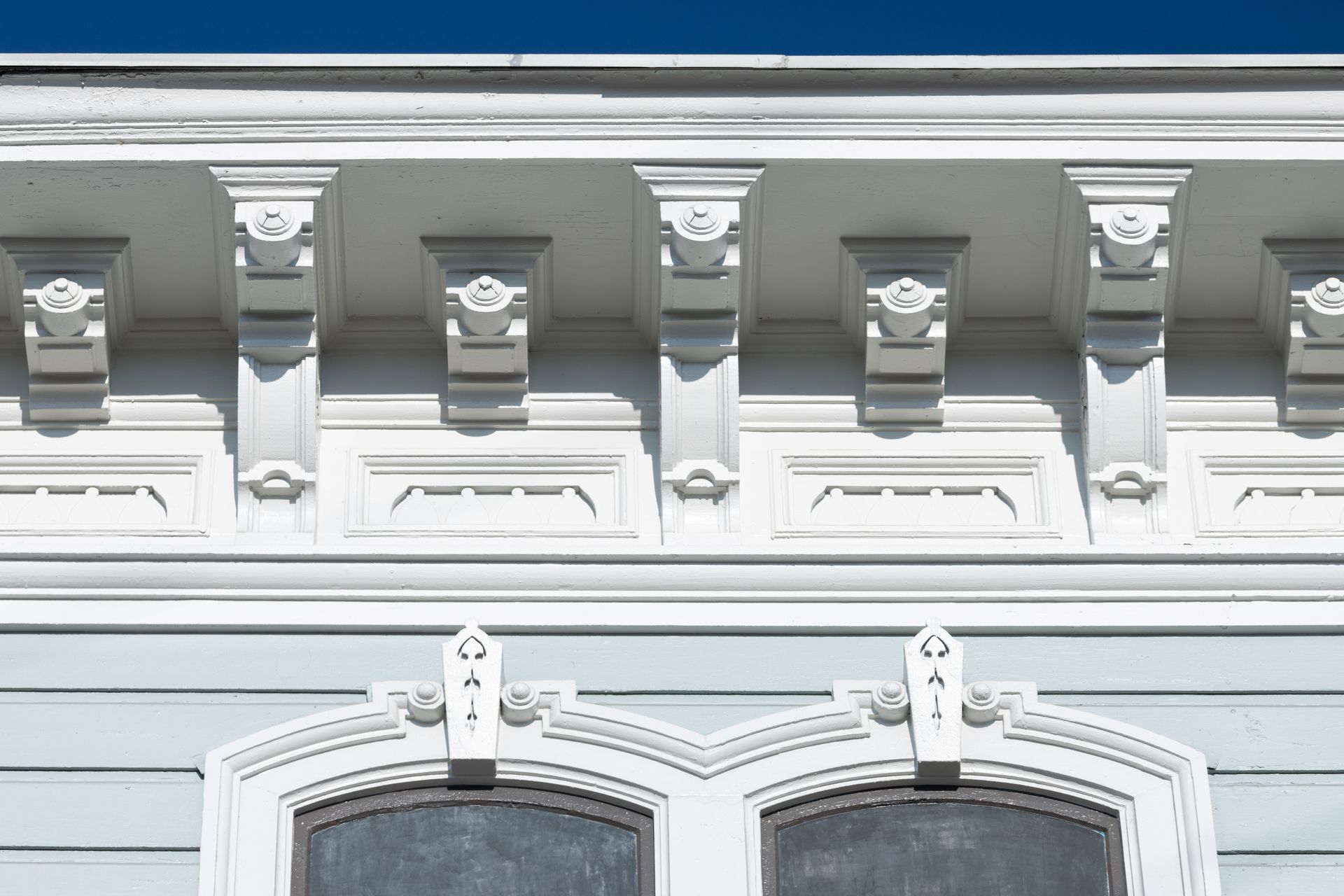 A close up of a white building with a window and a blue sky in the background.