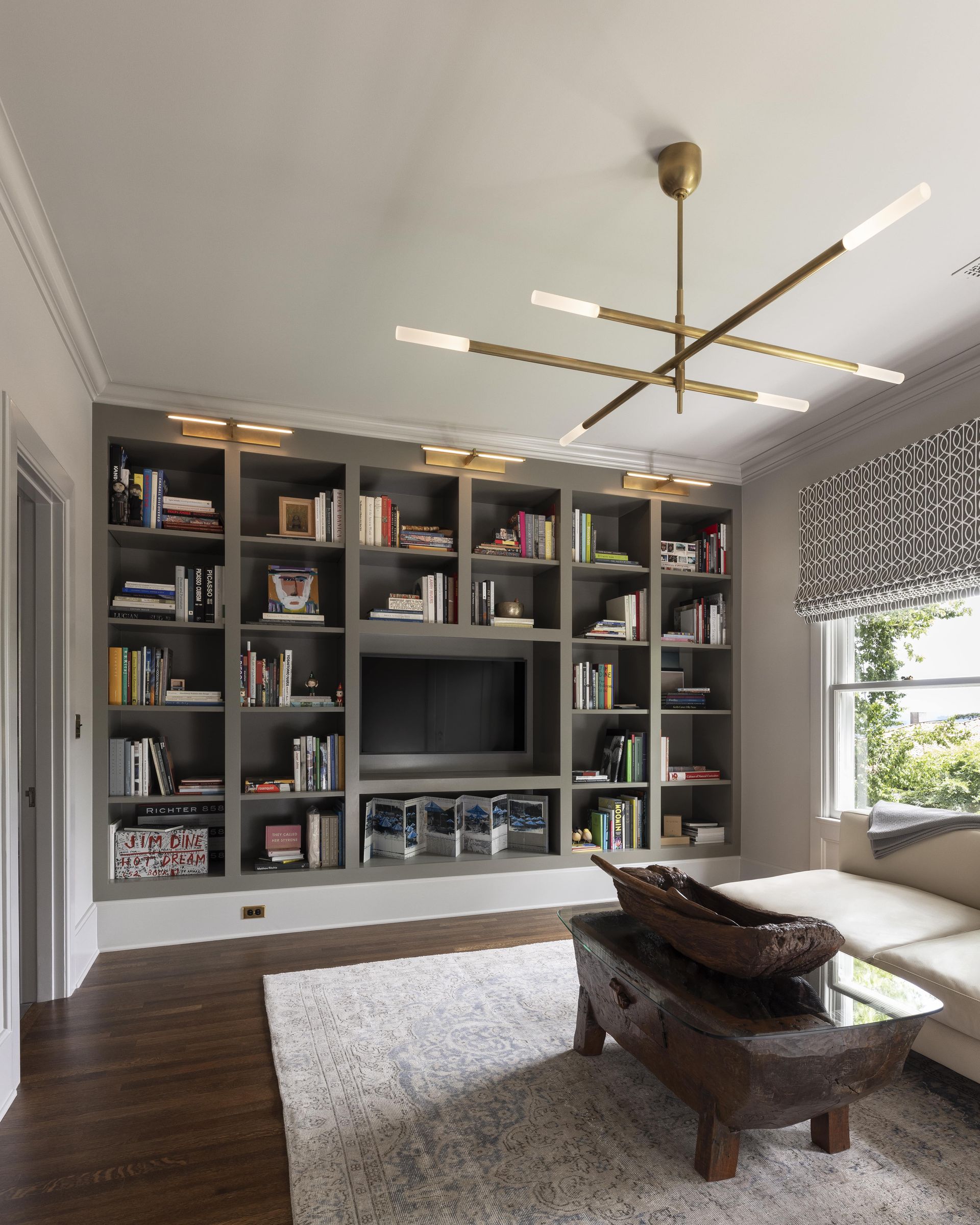 Custom shelving and contemporary light fixtures and furnishings in a colonial den.