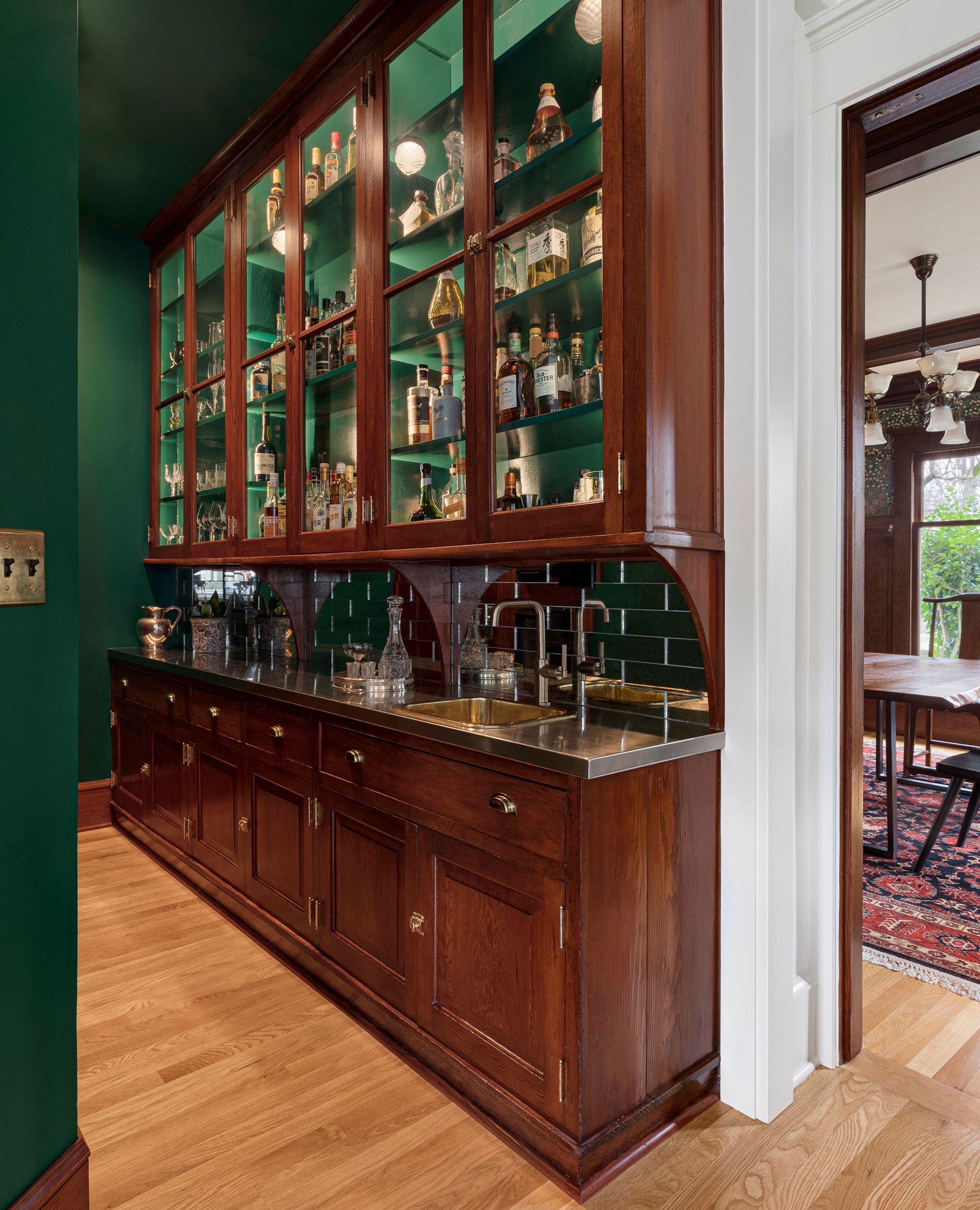 During a kitchen remodel of a 1911 Irvington Craftsman home, Arciform refurbished the original butler's pantry cabinets. The interior was painted the same rich green as the walls and ceiling, inner cabinet lighting was added, and space was repurposed as a well-equipped wet bar. 