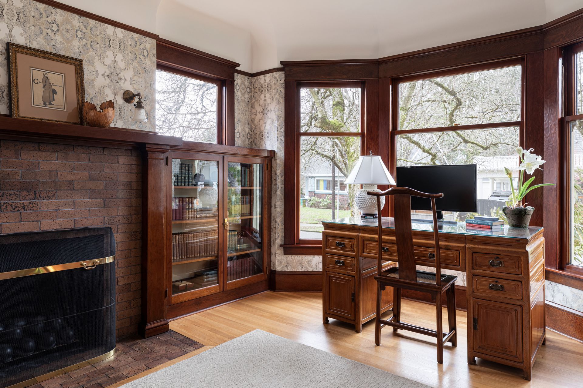 Cozy den with dark stained fir millwork, brick fireplace surround and an antique desk in the bay window.