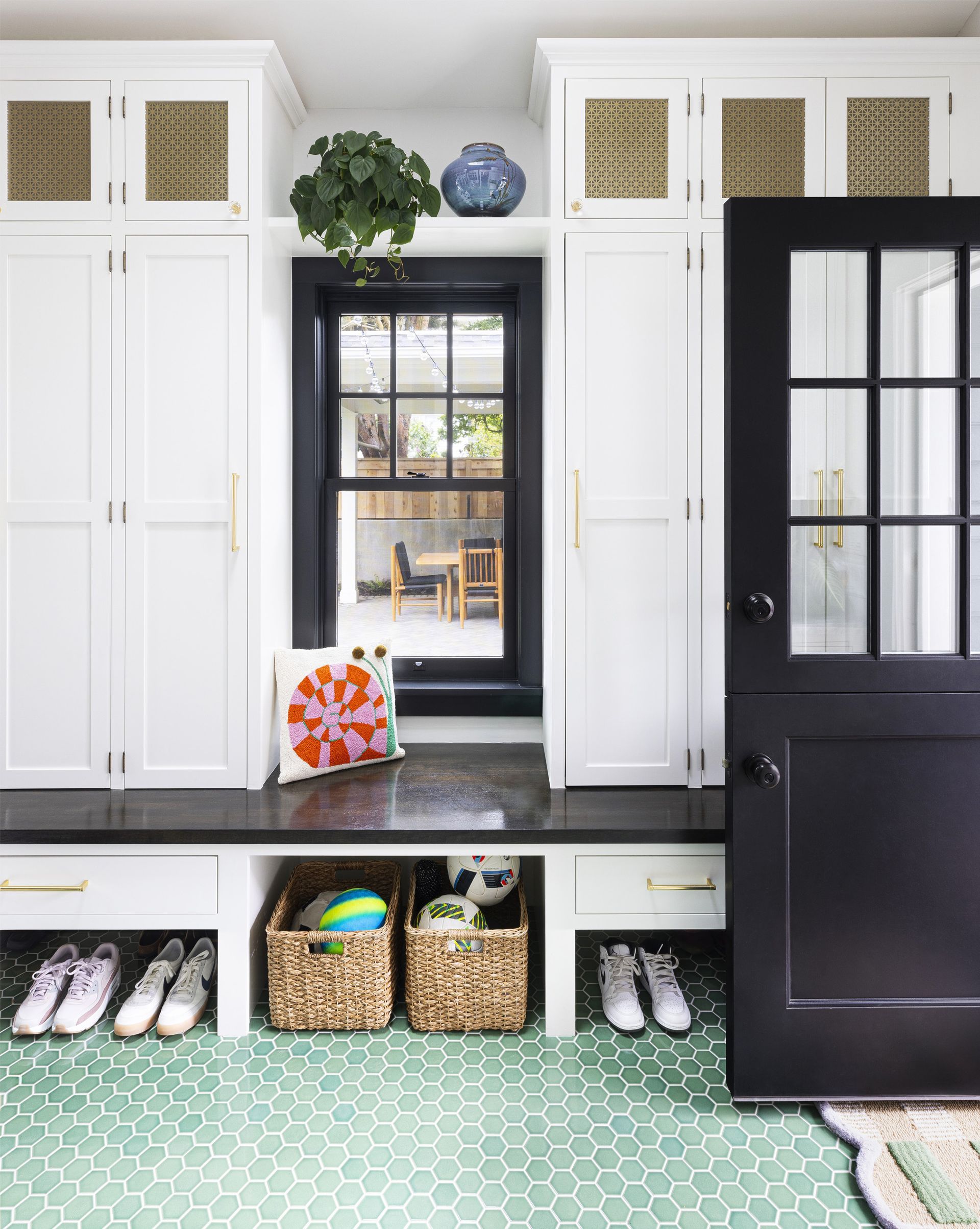 The small, new mudroom has full height cabinets for each family member above the perimeter bench with shoe storage below. A window lets in light and views of the new back patio. 