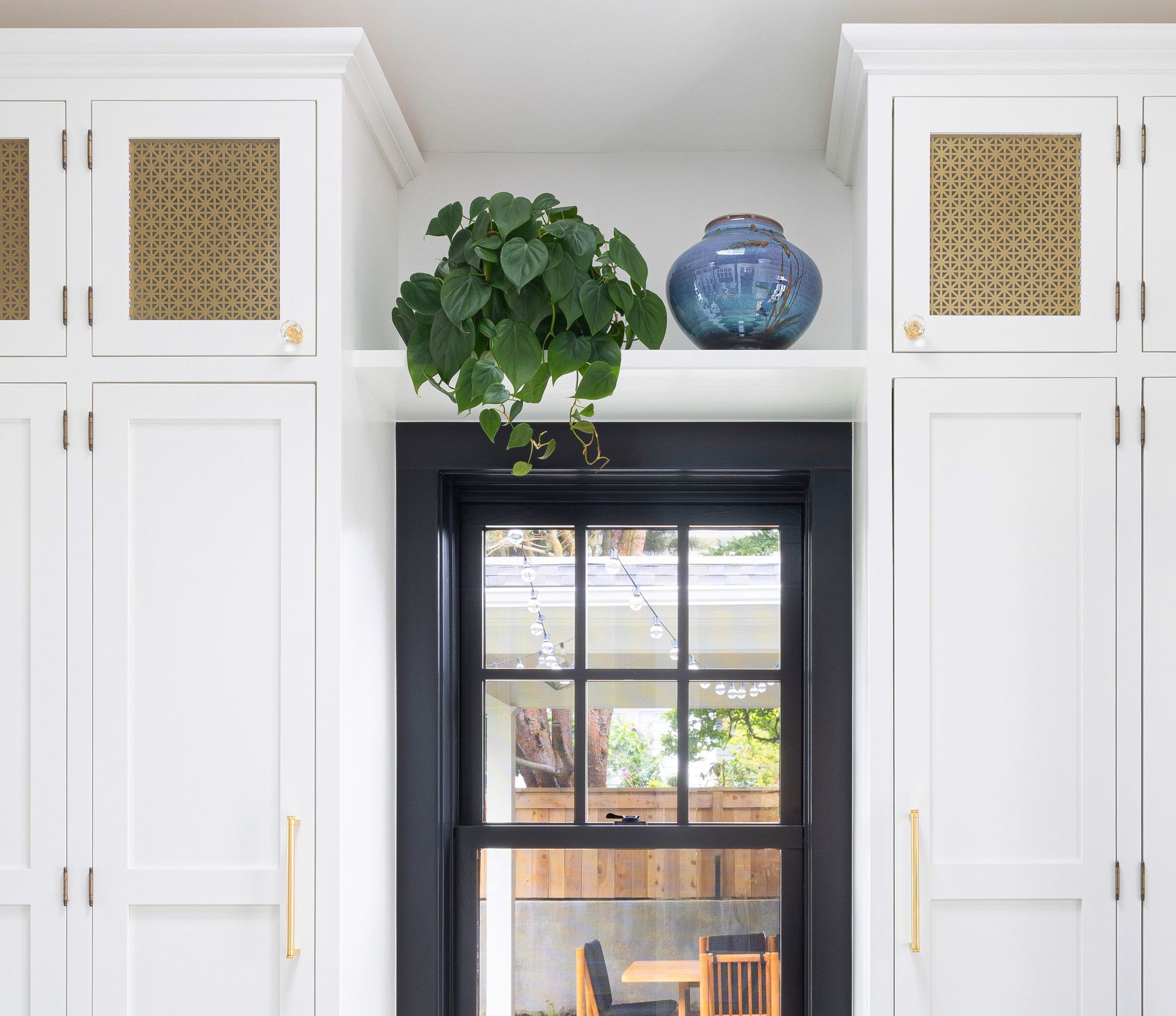 Plentiful full-height cabinets have perforated brass panels for ventilation and visual interest. The brass pulls and octagon crystal knobs tie in with the vintage hardware throughout the house.