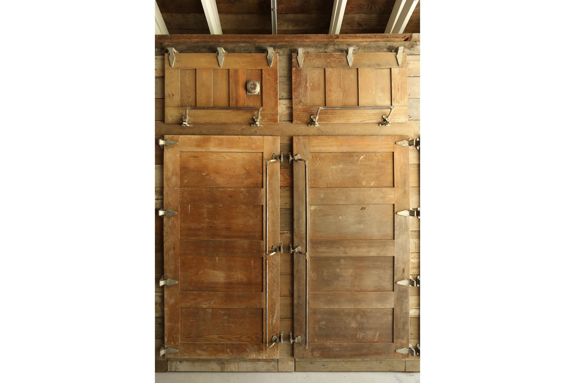 In one corner, new closets paneled in ice¬box doors from an old dairy hide a modern fridge and storage, and in another sits a broad, salvaged seed-company chest with many tiny drawers. 