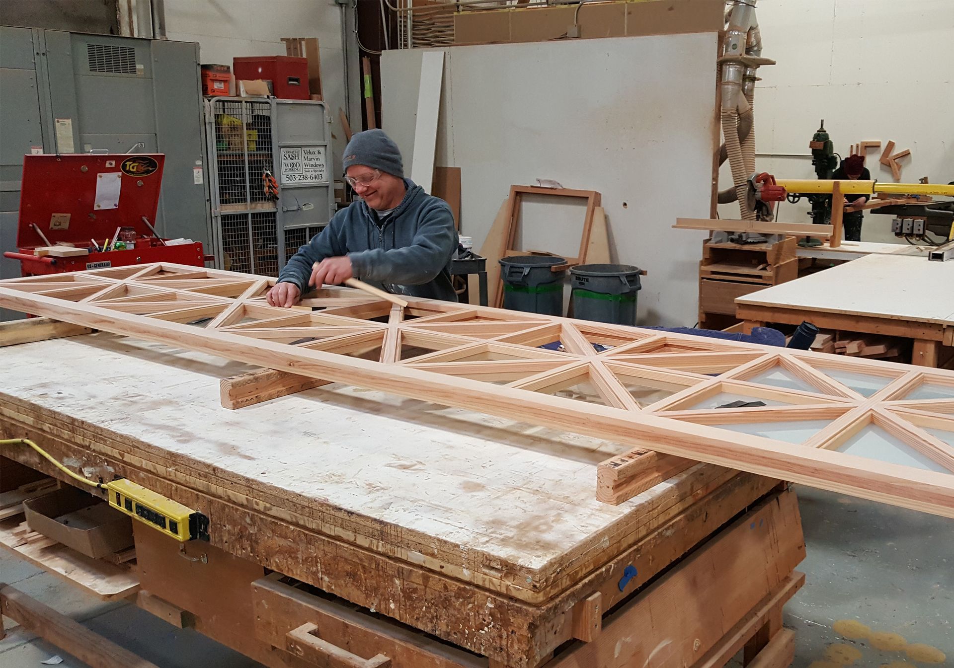 A man is working on a wooden structure in a workshop.