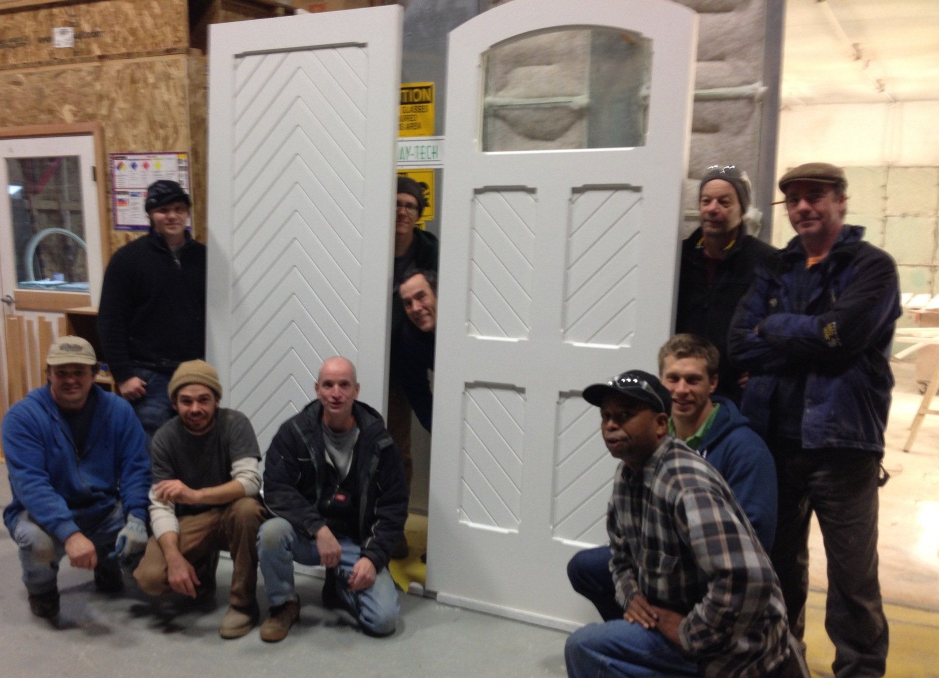 A group of men are posing in front of a white door