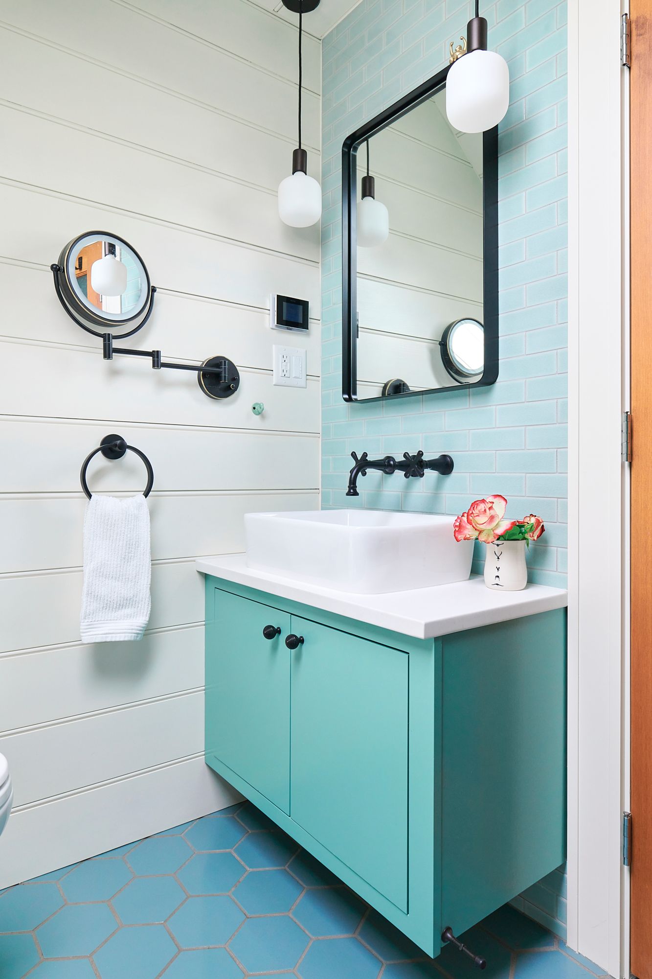 The hallway laundry closet is concealed with a rolling Chinese screen & features cheery wallpaper & built ins.