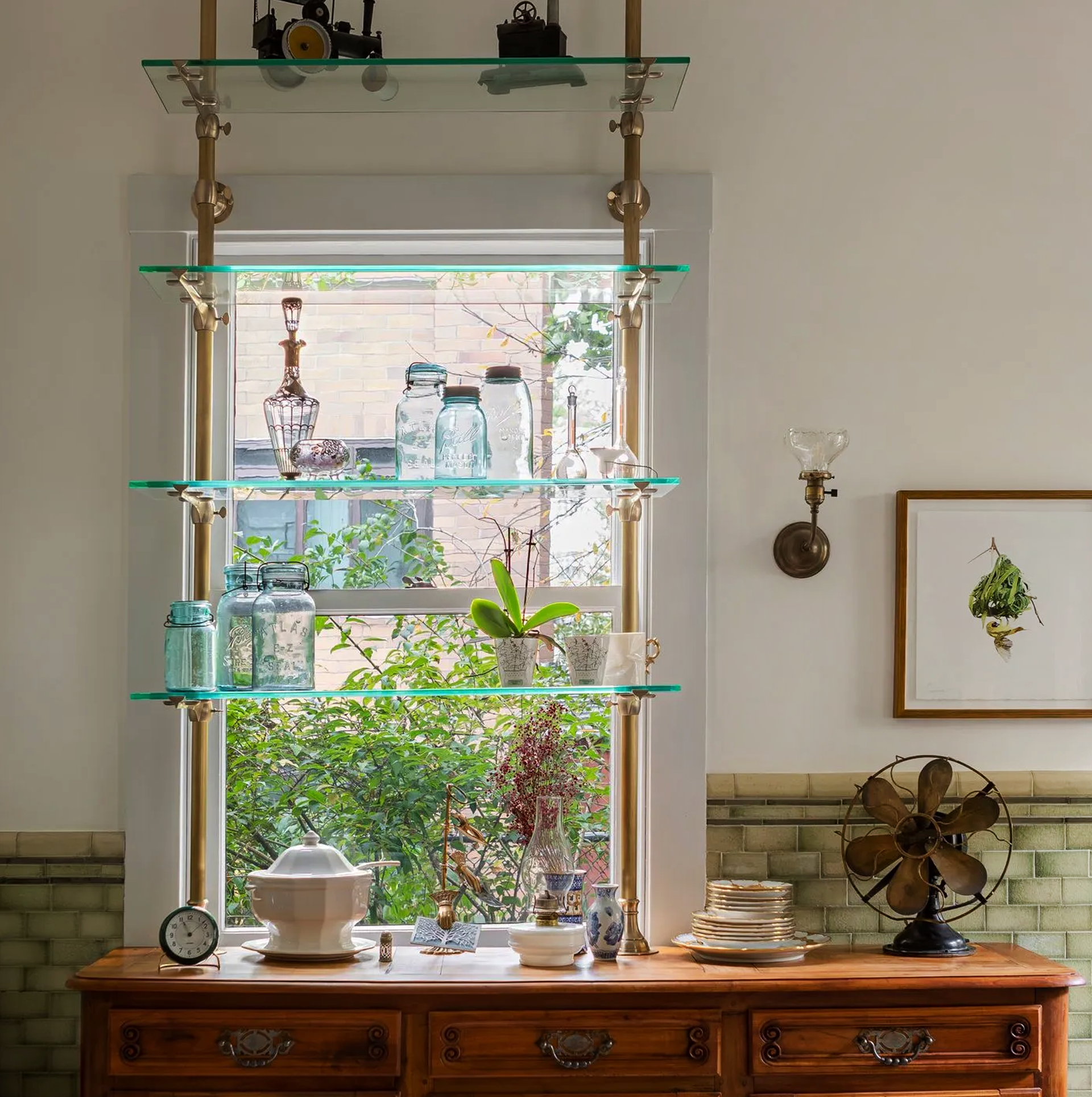 French bistro shelving with glass shelves  mounted in front of a window adds a bit of storage while preserving the maximum amount of light.