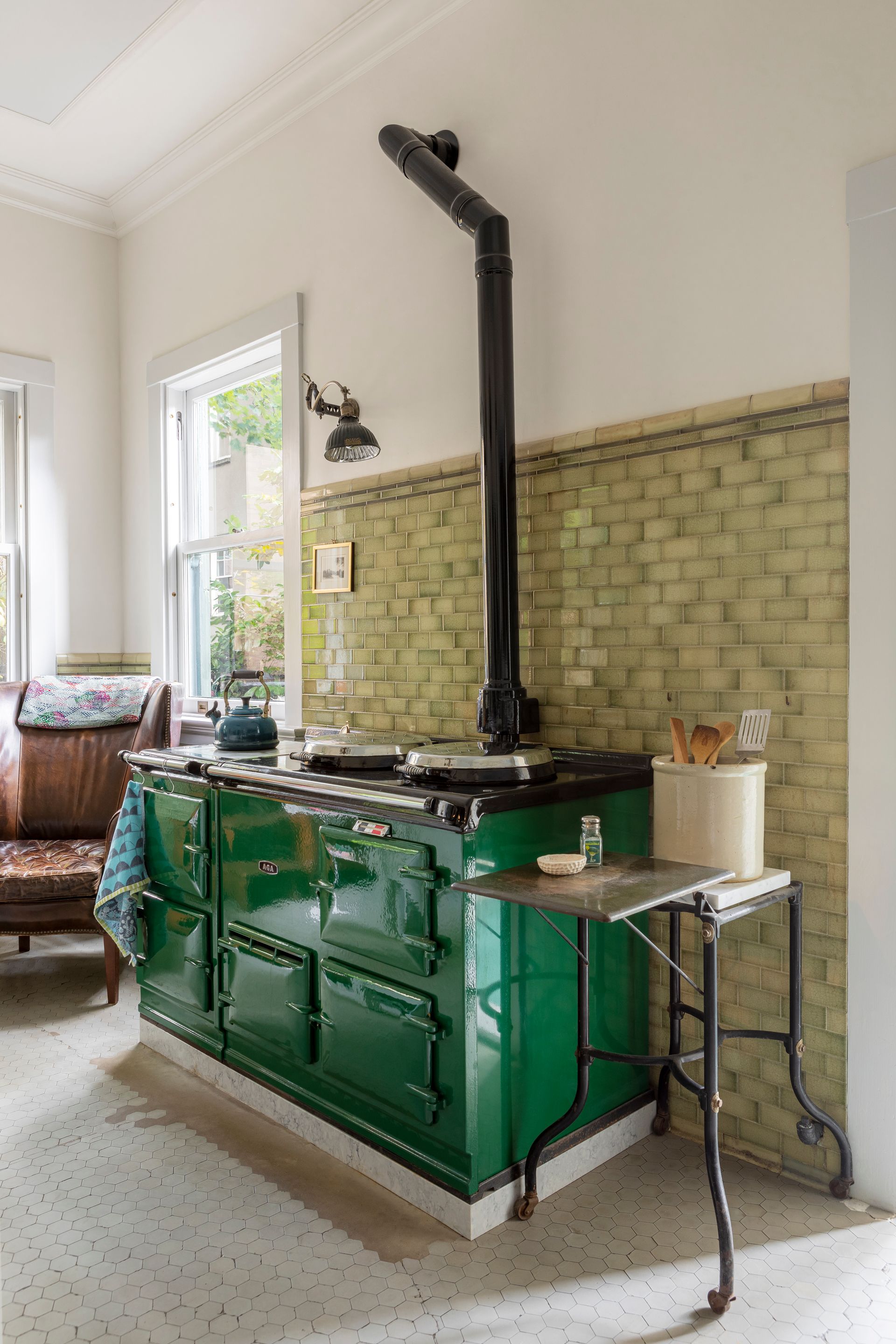 A kitchen with a painting on the wall above the stove.