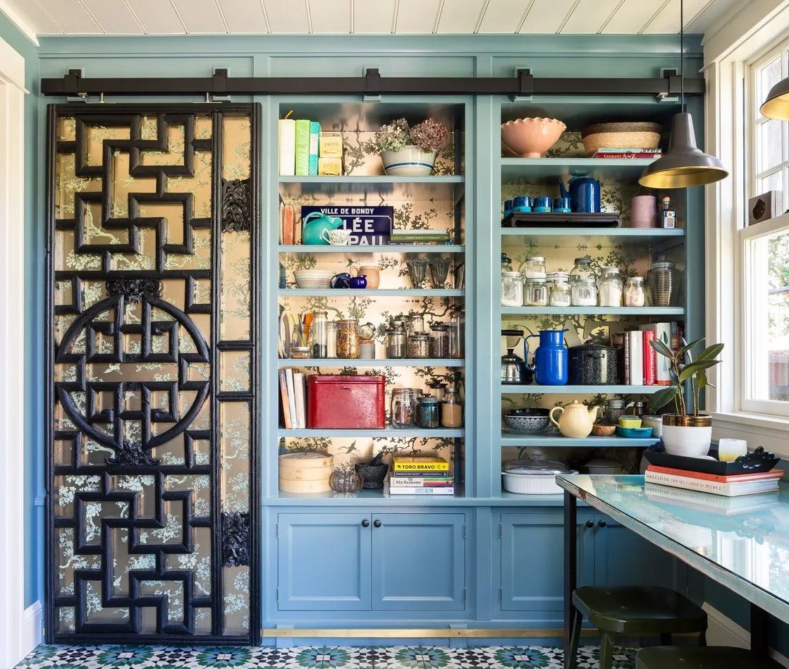 The back of this floor-to-ceiling pantry cabinet is lined in a shimming Chinese-inspired wallpaper. The pattern continues on the sliding door panels. 