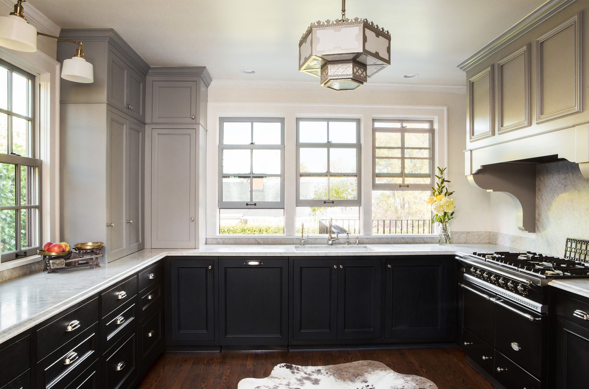 Wide view of the remodeled kitchen with ebonized cabinets, plentiful windows and an antique pendant lamp overhead.