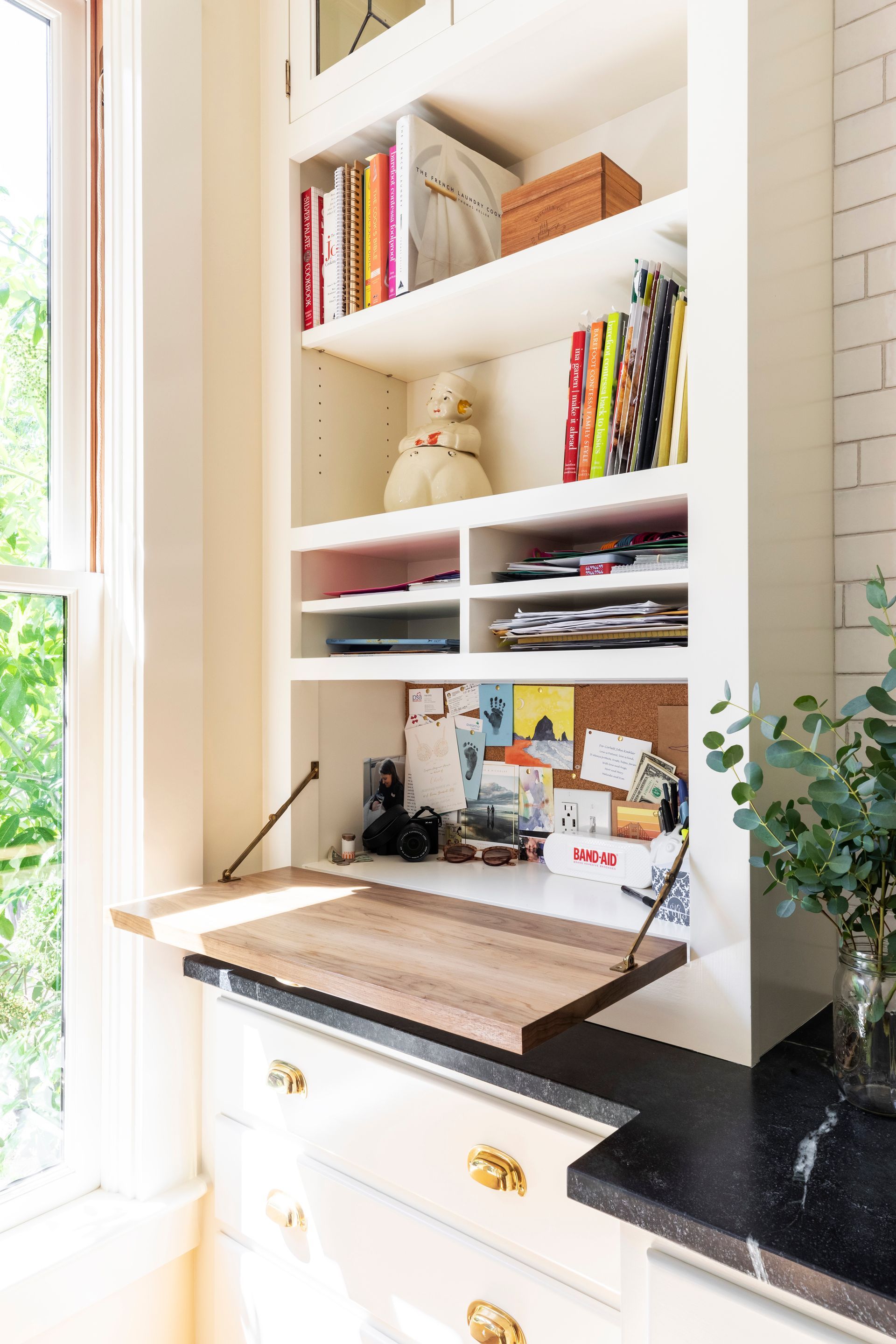 In the back corner of the kitchen, a custom billpay area has a tip-down desk with open shelves above