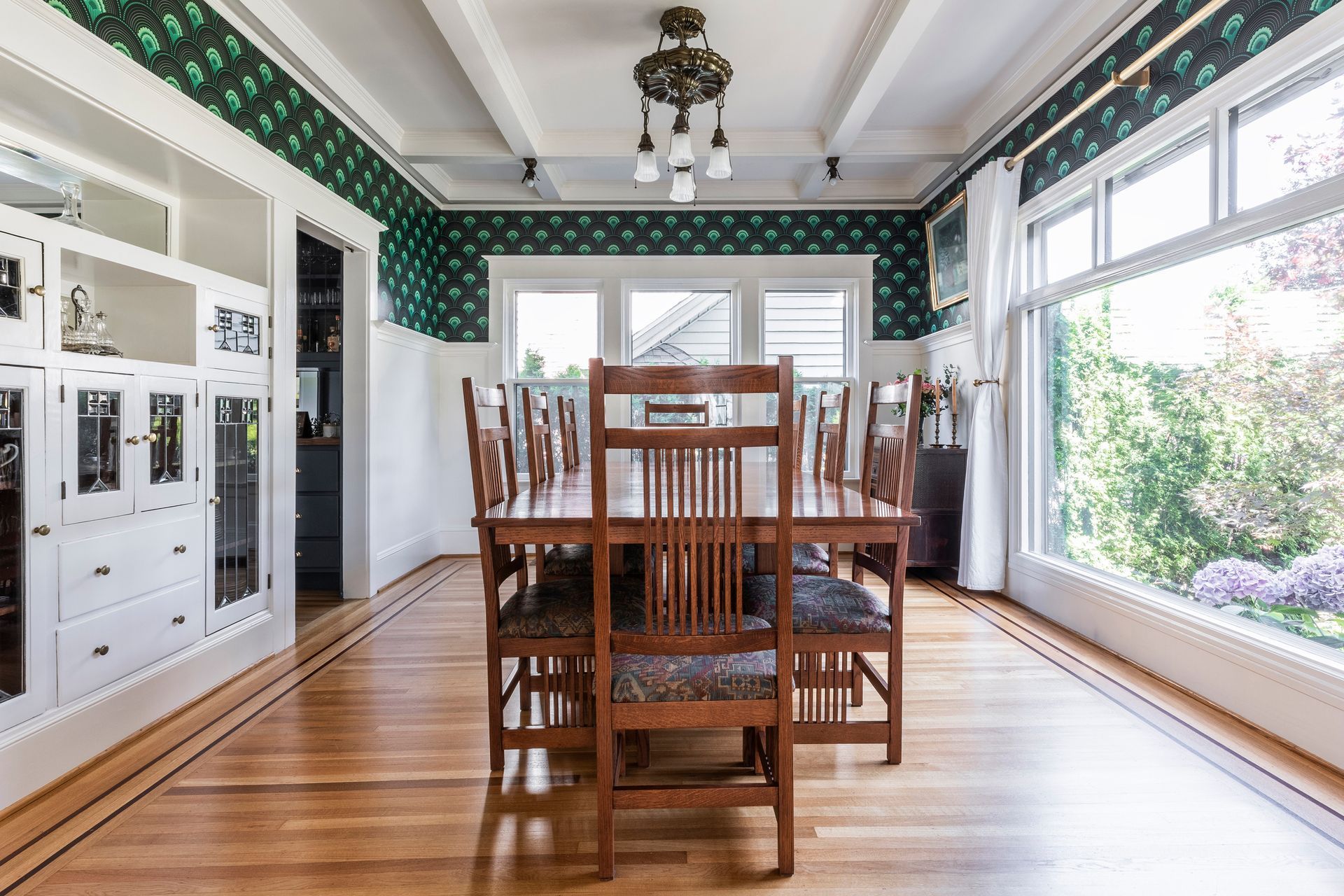 The dining room’s great bones boast rich emerald-green art deco wallpaper to contrast with white millwork