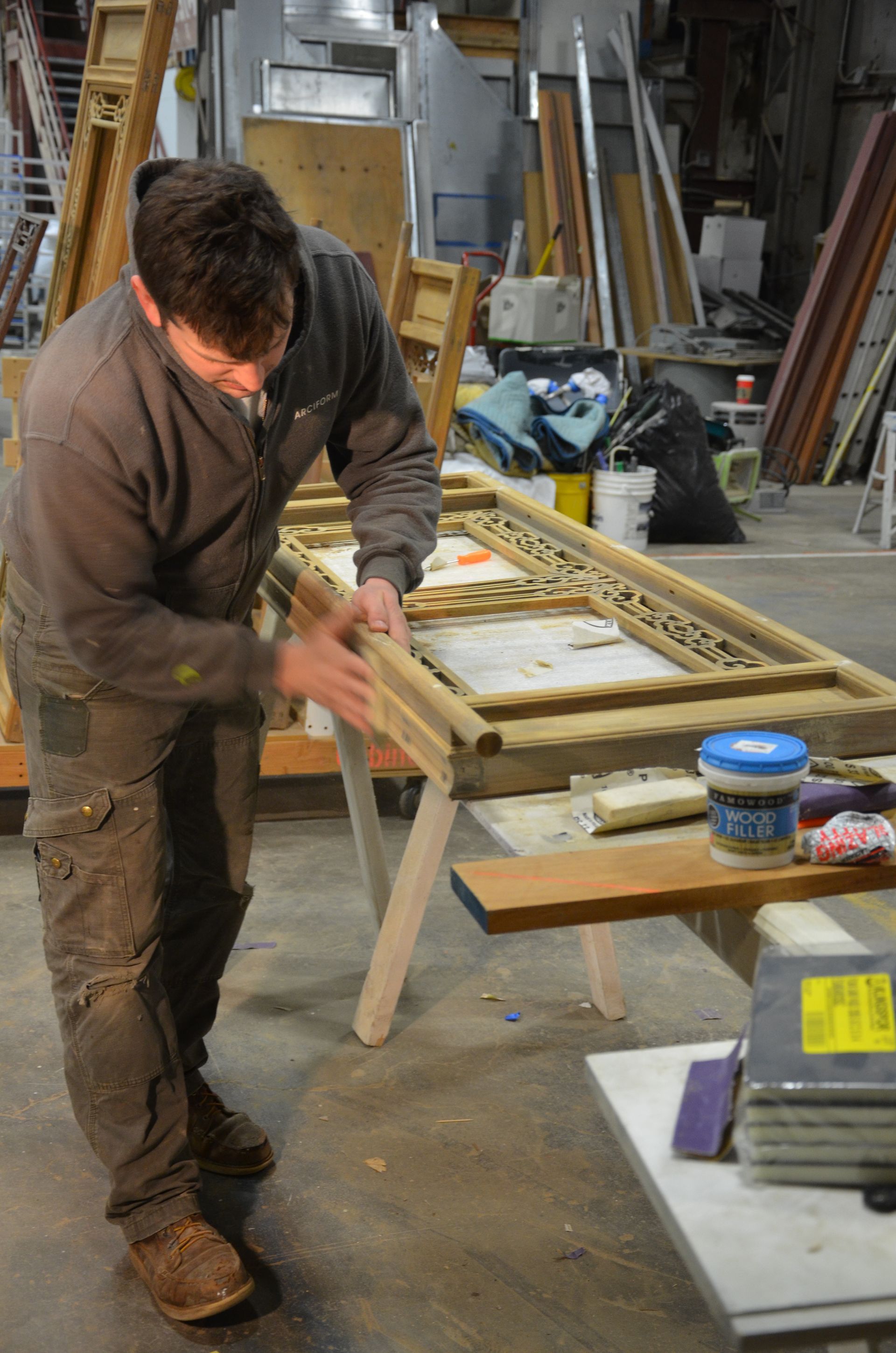 A man is working on a piece of wood in a workshop.