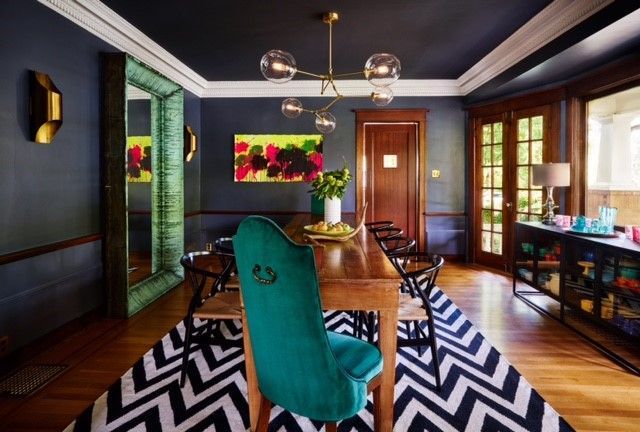 A dining room with a blue chair and a black and white rug