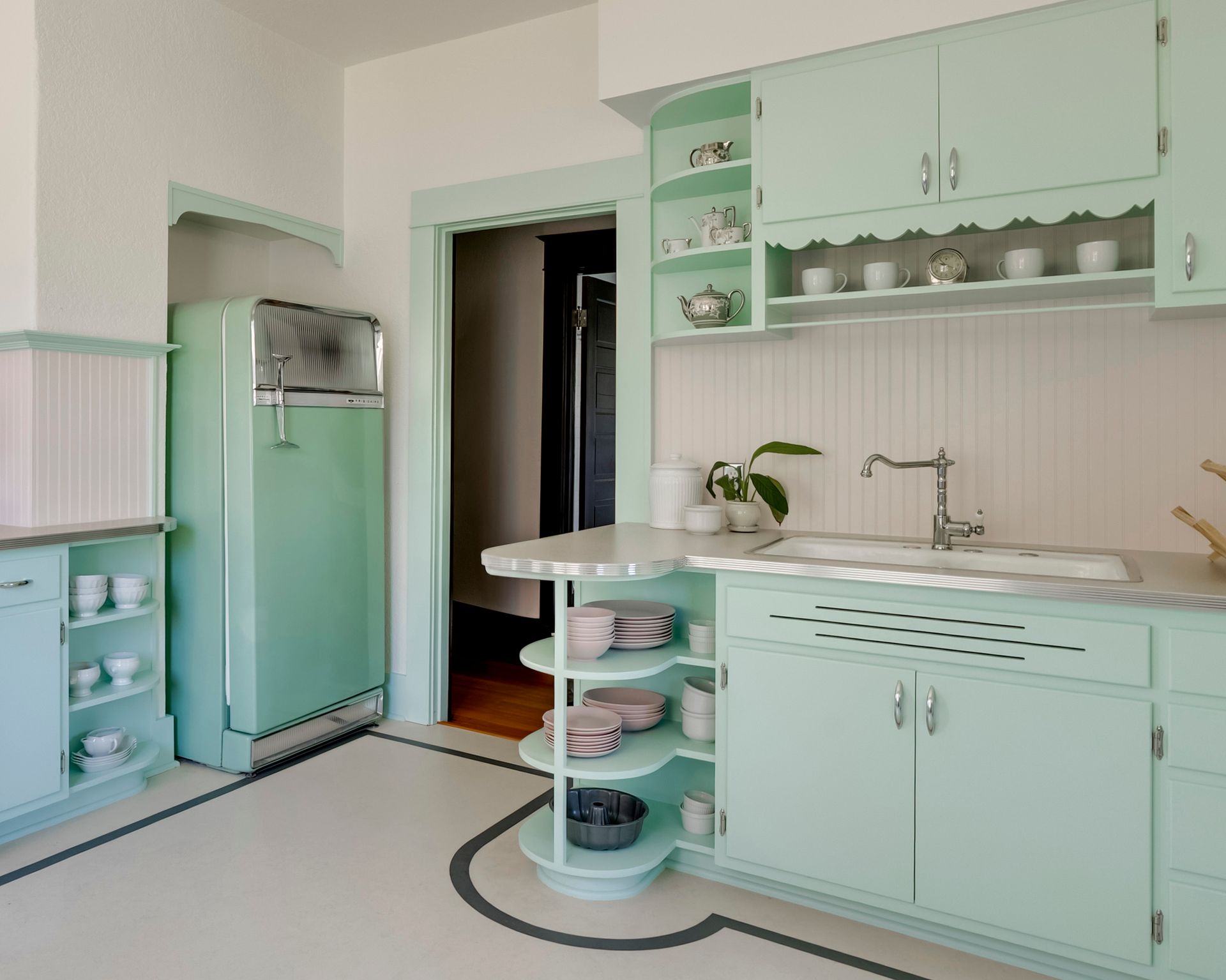 For the kitchen of an Oregon City bungalow, Arciform incorporated curved open shelves into the vintage style cabinets. Over the sink an additional shelf with a scalloped valance keeps mugs close at hand.