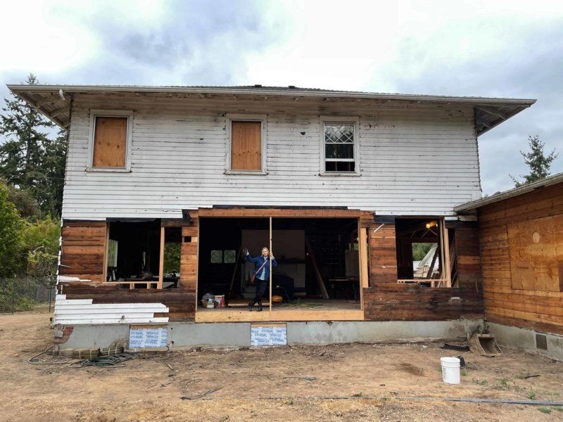 A man is standing in front of a house that is being remodeled.