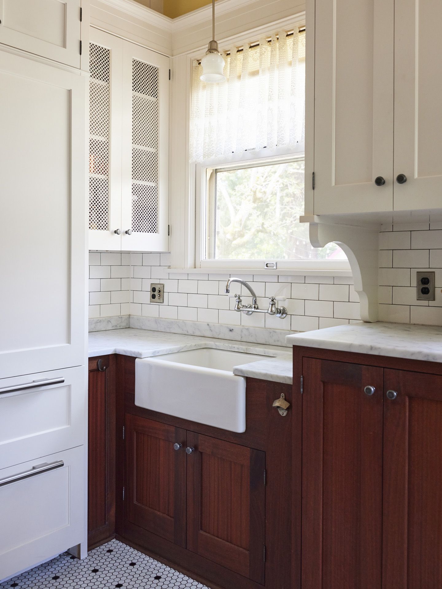 A generous farm style prep sink at the back wall has a backyard view and plentiful cabinets.