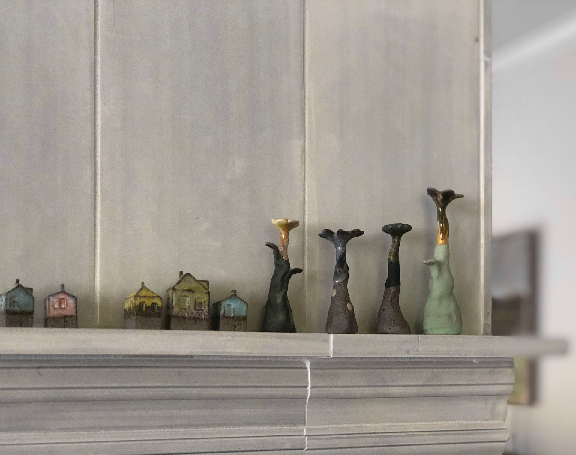 The narrow fireplace mantle is the perfect spot to display the client's collection of miniature clay sculptures and houses.