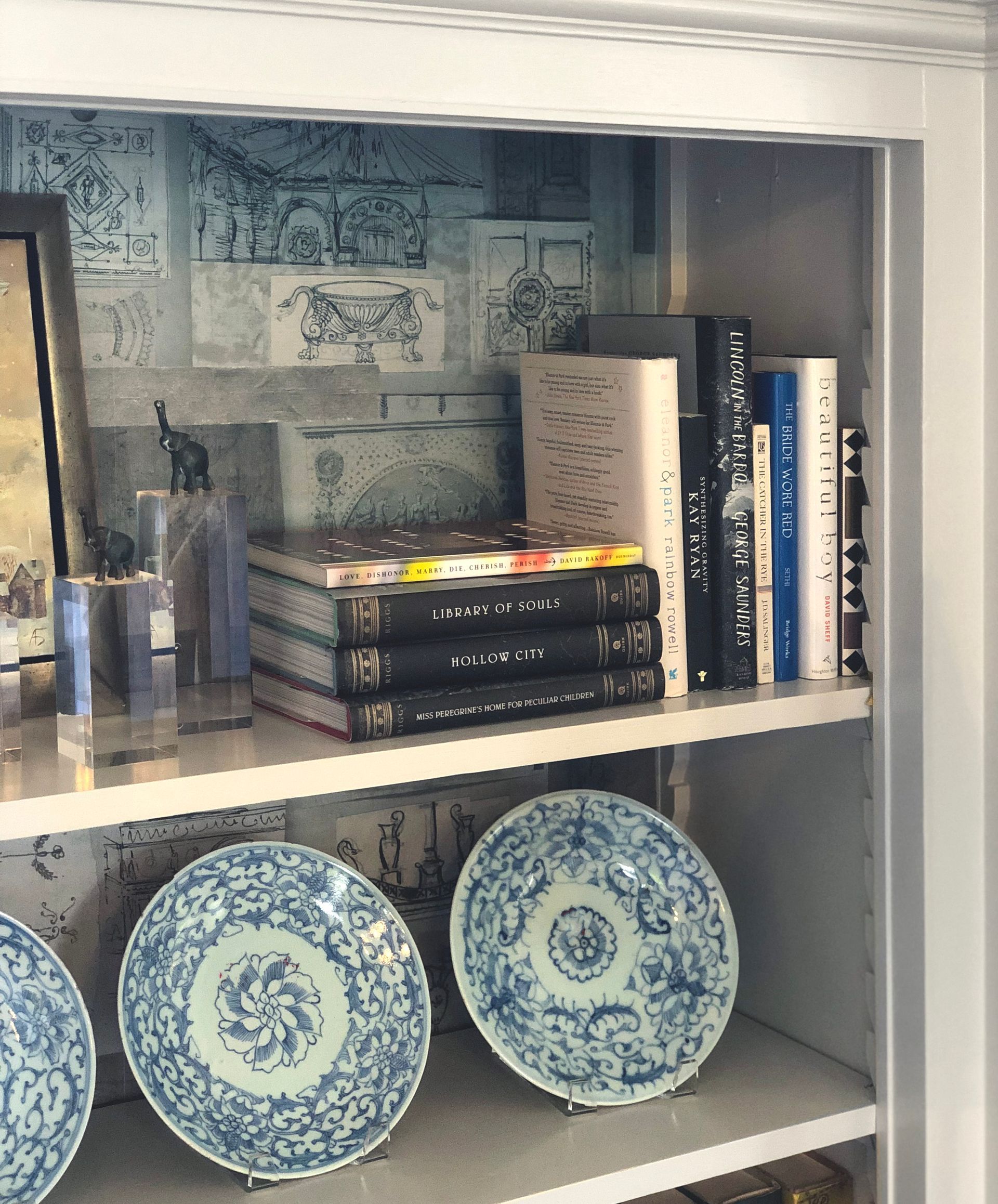 Bookcase lined with wallpaper that coordinates with the items on display.