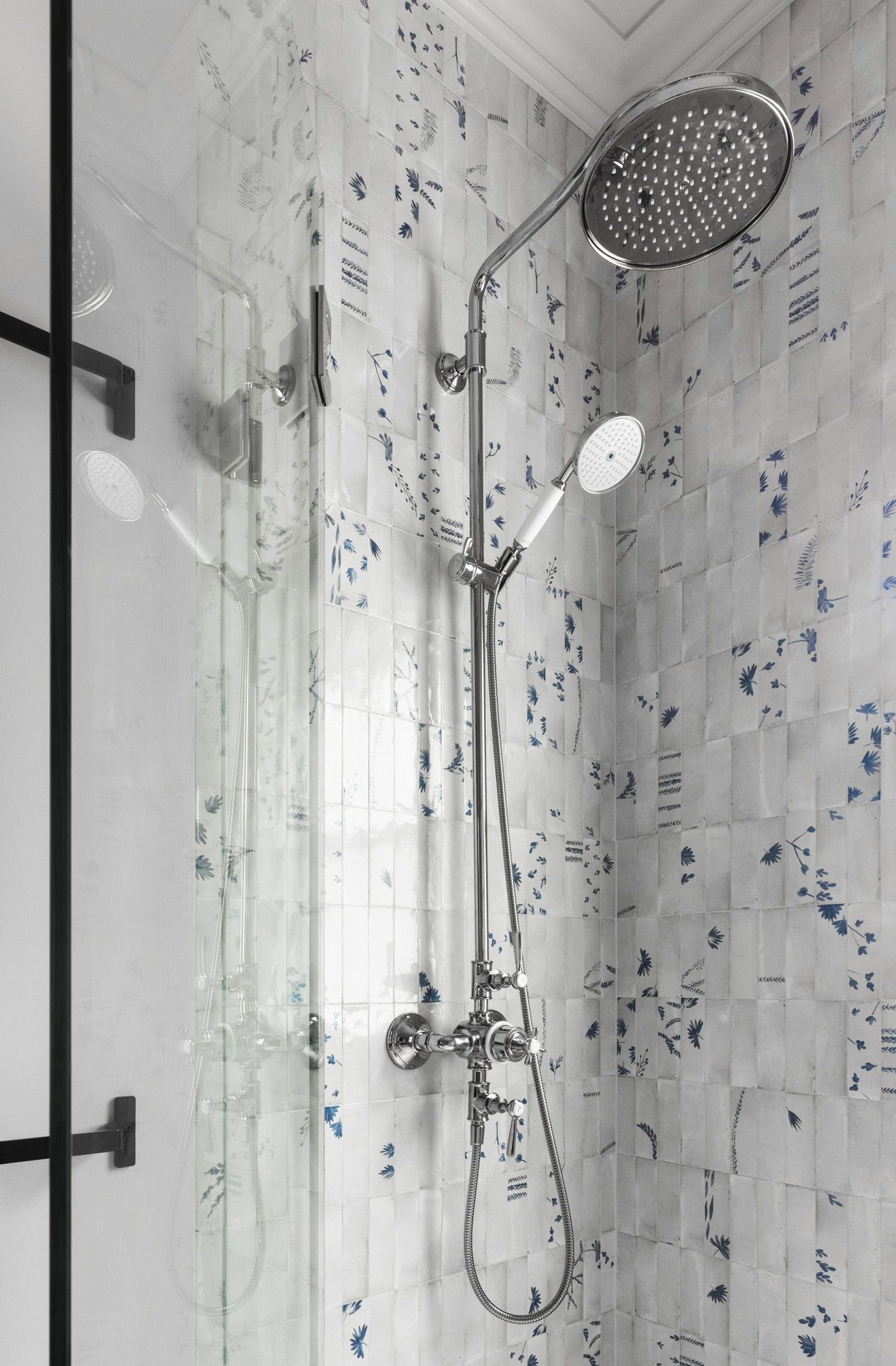 Shower stall with classic shower assembly and floral-patterned tile.