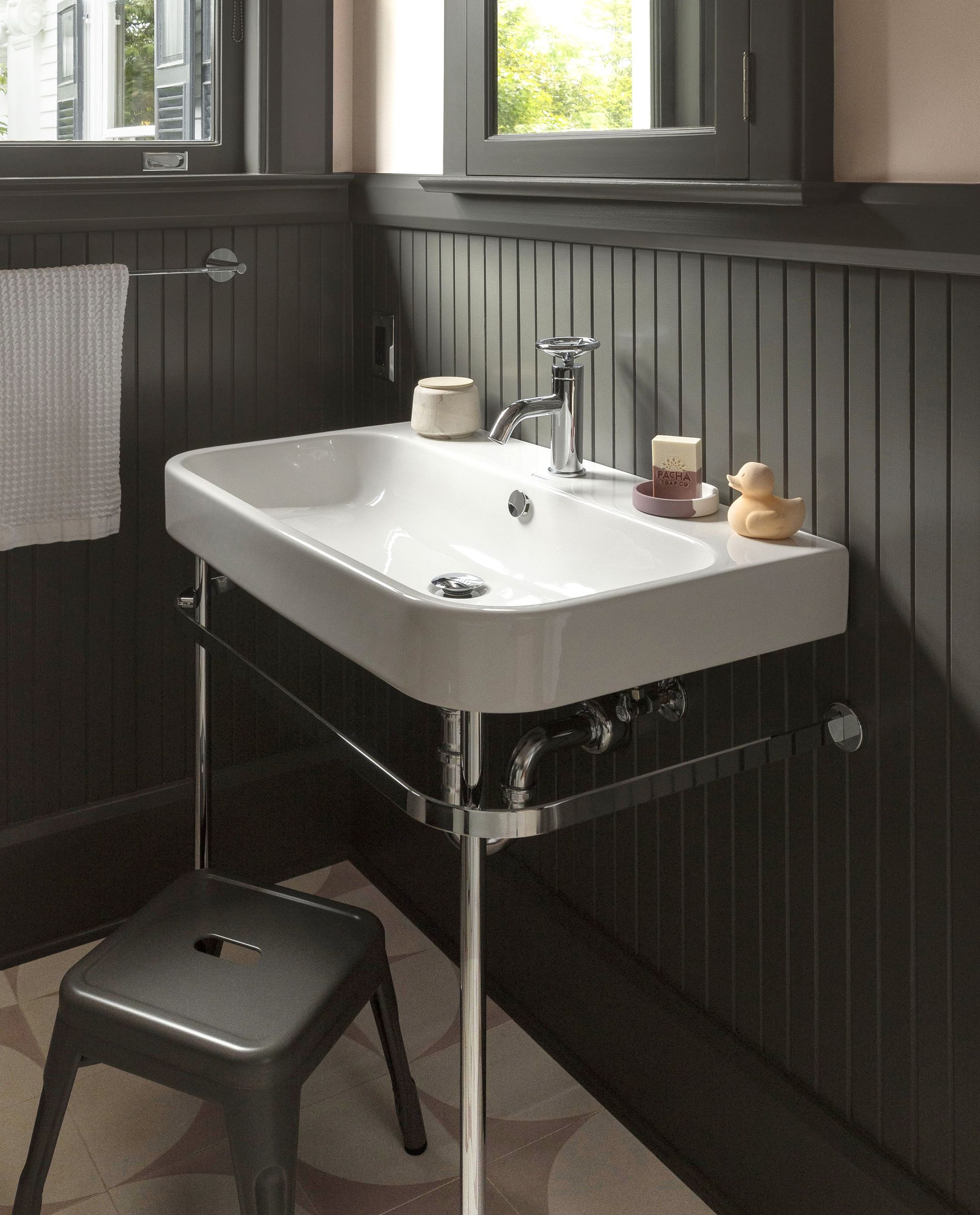 Contemporary porcelain console sink in front of beadboard wainscot in a bathroom.