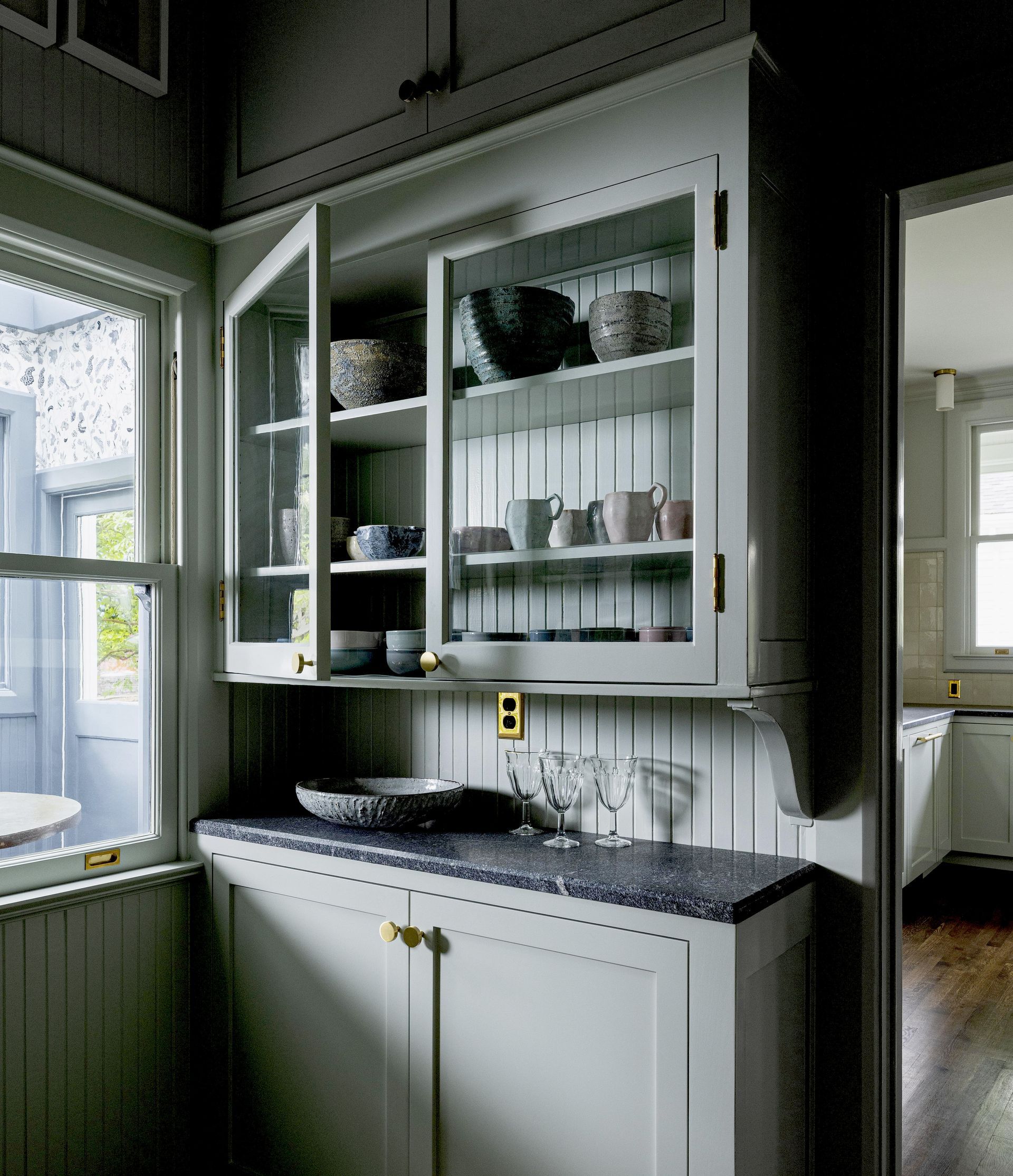 A restored colonial butler's pantry with the wallpapered sunroom beyond.