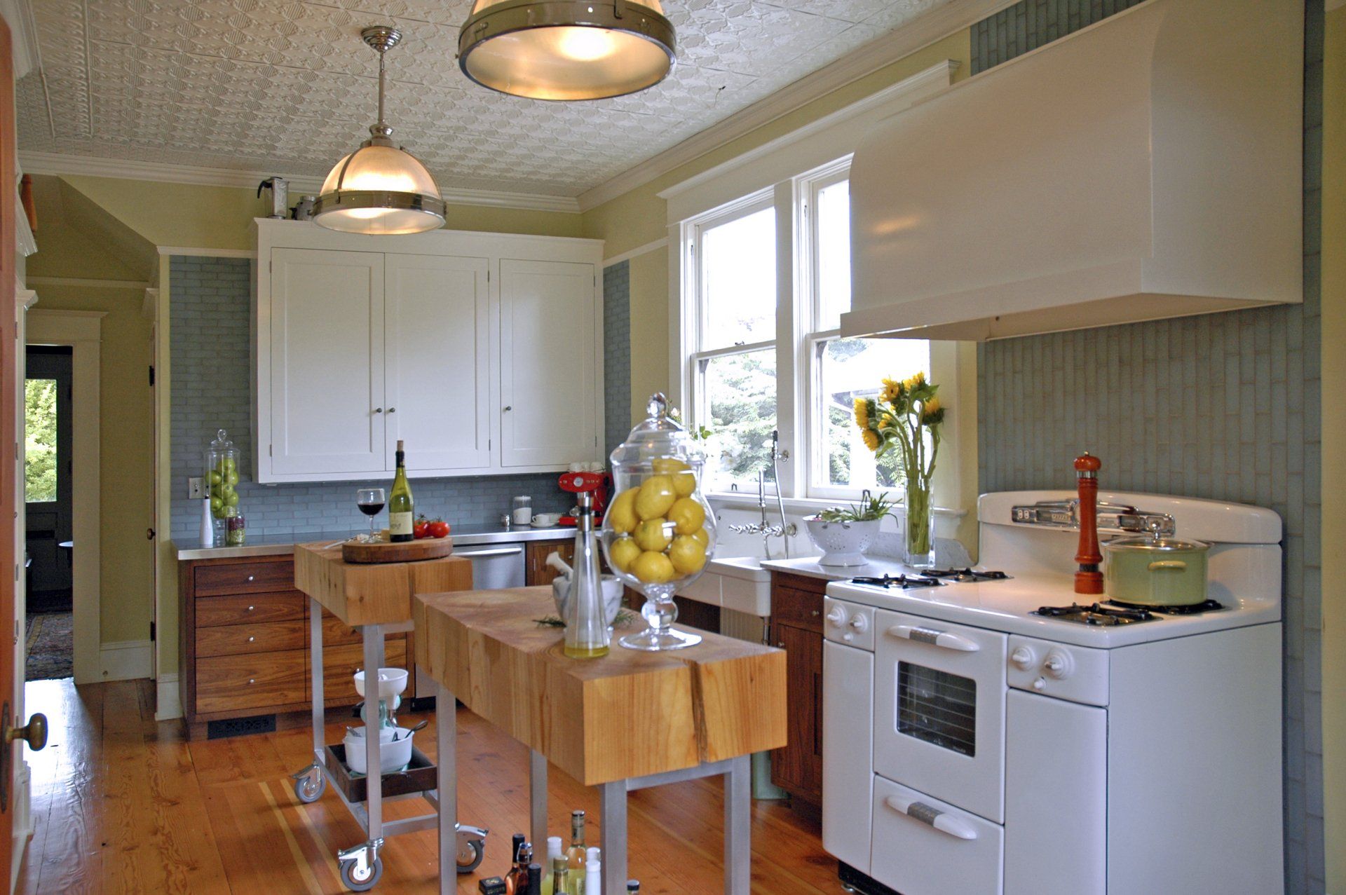 In the cheery, charming kitchen with its walnut cabinets, pressed tin ceiling, Carrara marble counters, salvaged stove & sink. 
