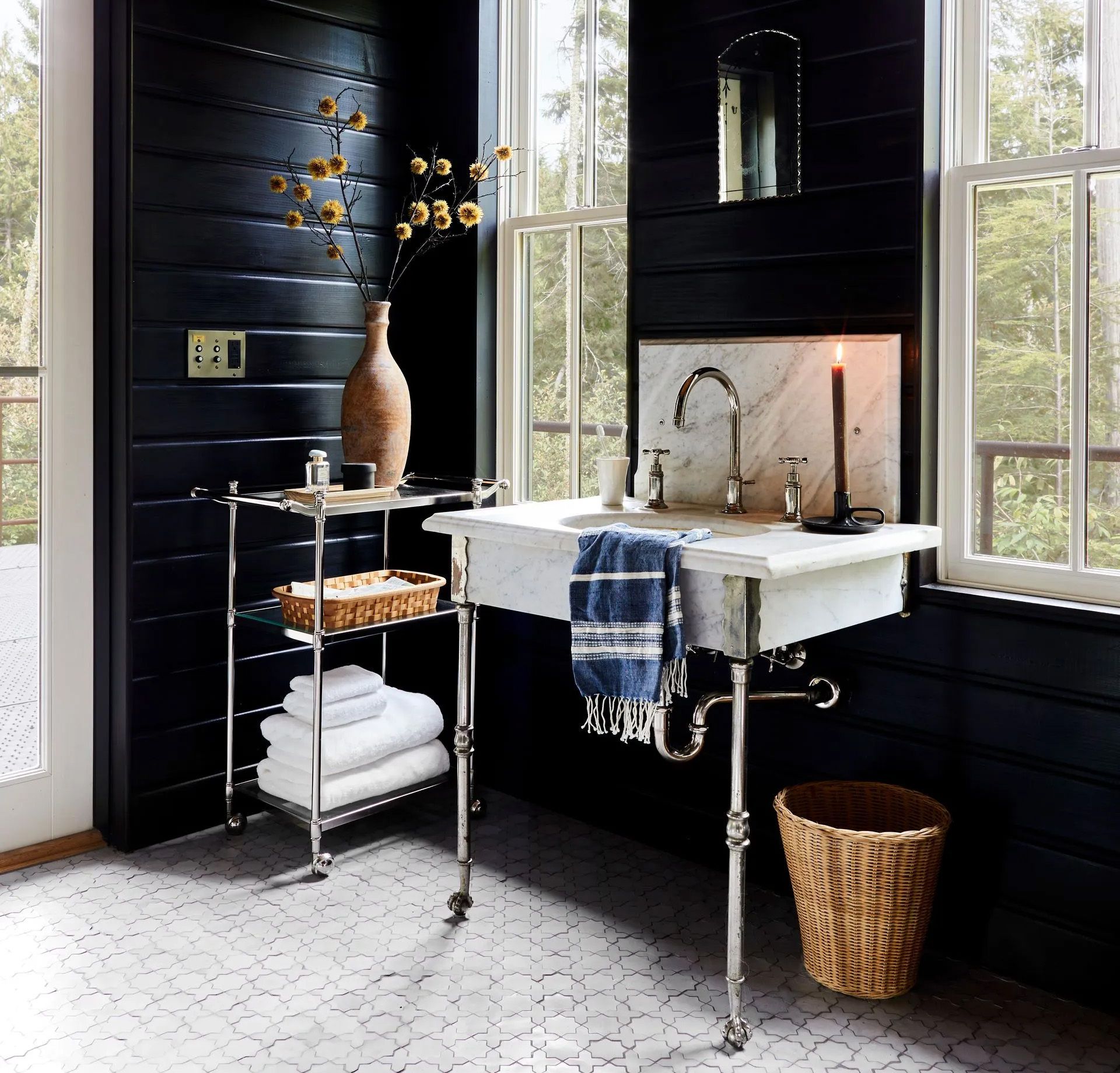 Tongue-and-groove walls painted black,  Zellige floor tiles, and a marble and nickel console sink create a space that's rustic and moody, yet sophisticated. 