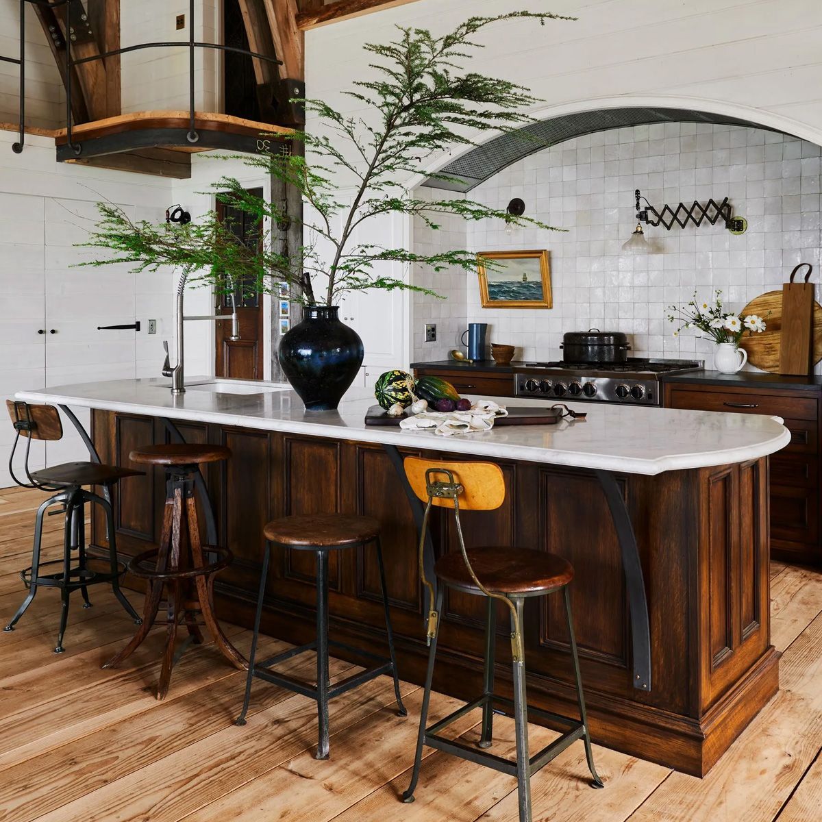 Blending dark stained wood, custom iron supports, and a gracious marble countertop, the island recalls vintage shop or bakery counters.