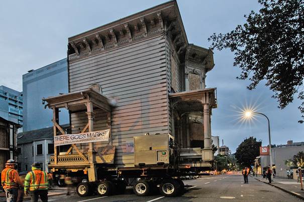 A large house is being moved down a city street