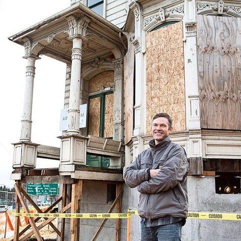 A man standing in front of a building with a yellow caution tape around him