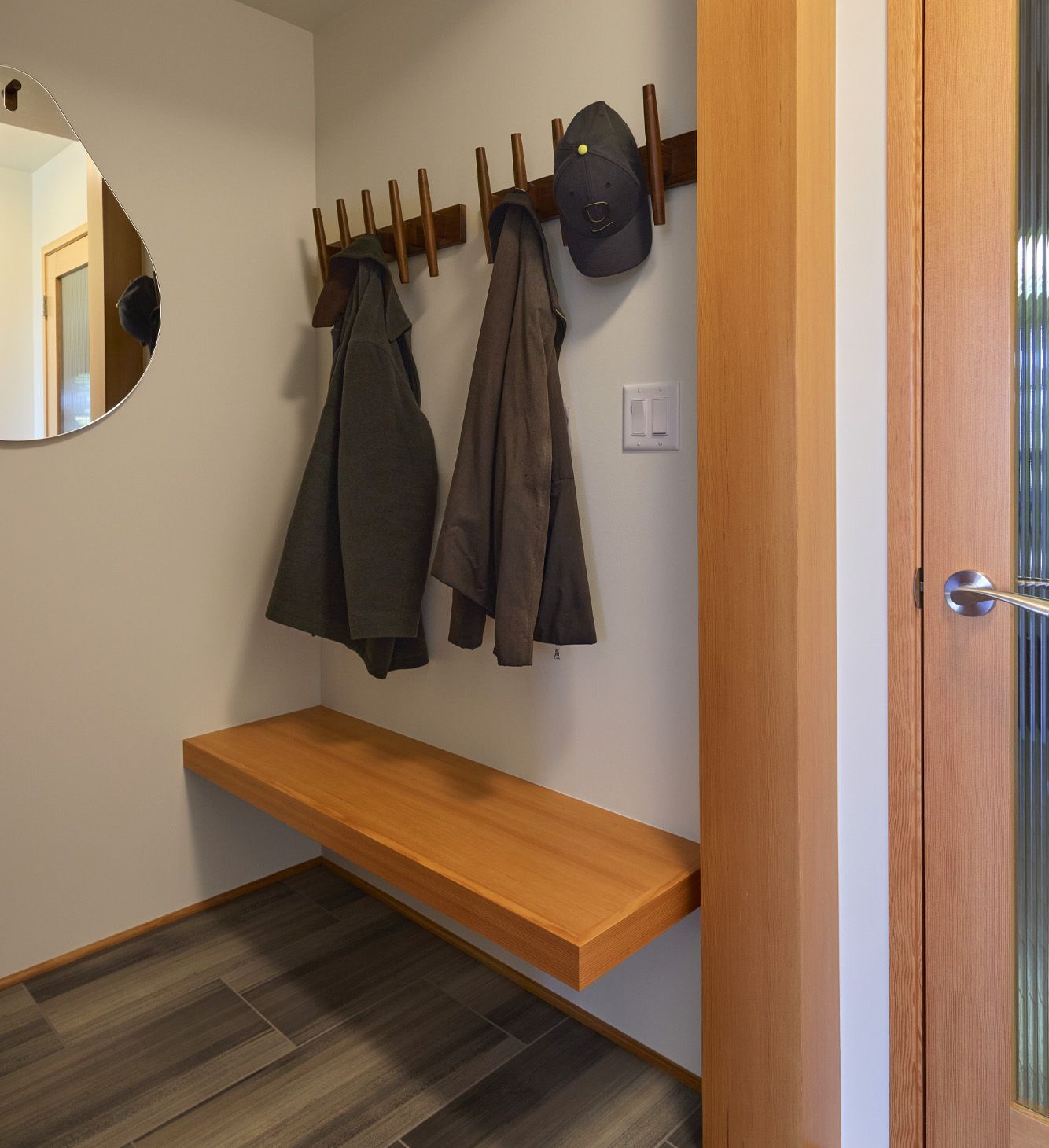 A tidy mudroom under the main stairs plenty of hooks for hats and coats, a bench for taking off muddy shoes and a door to keep things looking tidy.