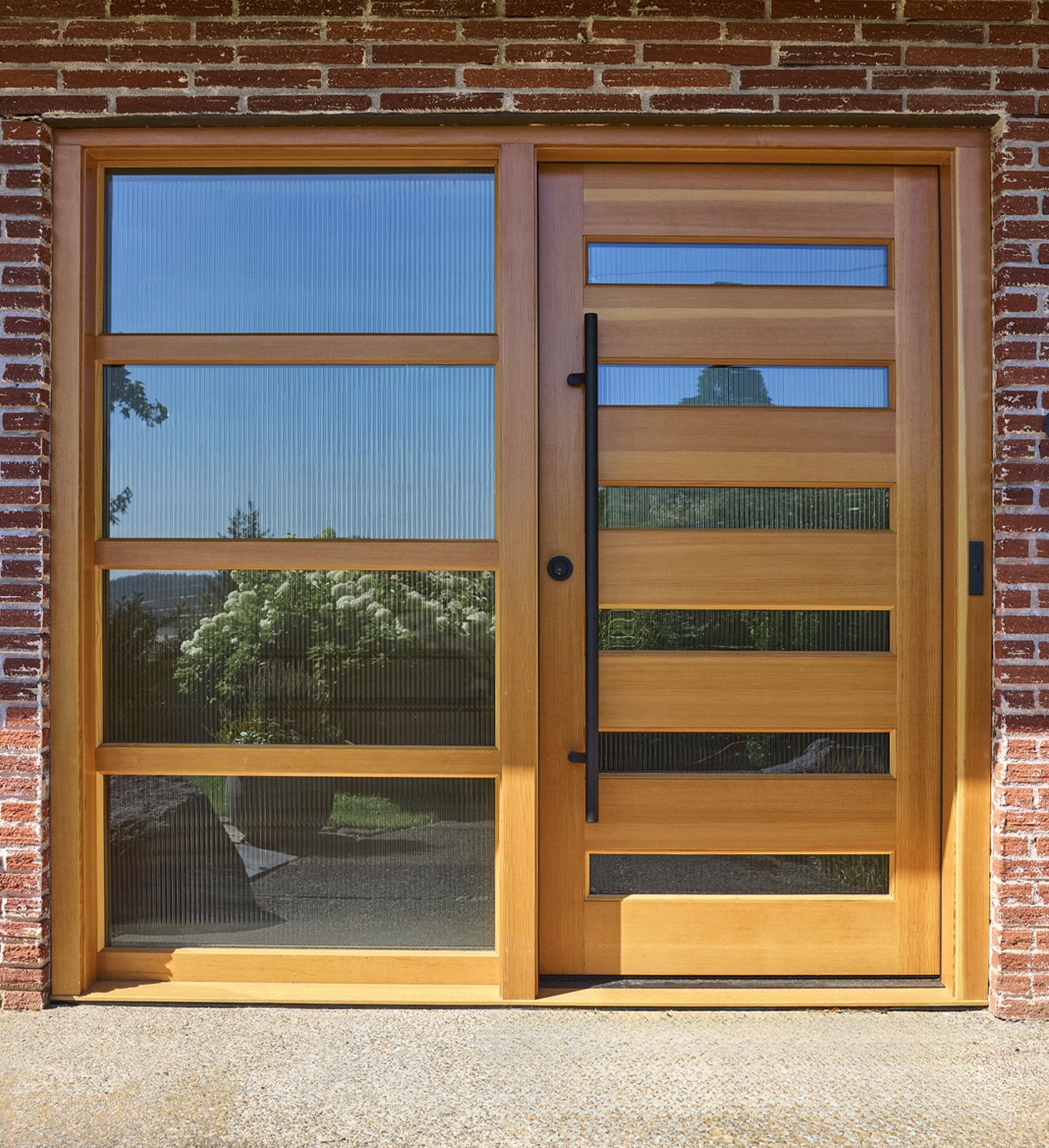 The front door and sidelite were custom made in our shop, designed by the client. In stained wood and slatted glass, it lets light into the entry.