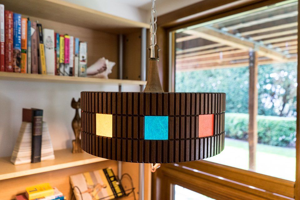 A lamp hanging from the ceiling in front of a bookshelf filled with books.