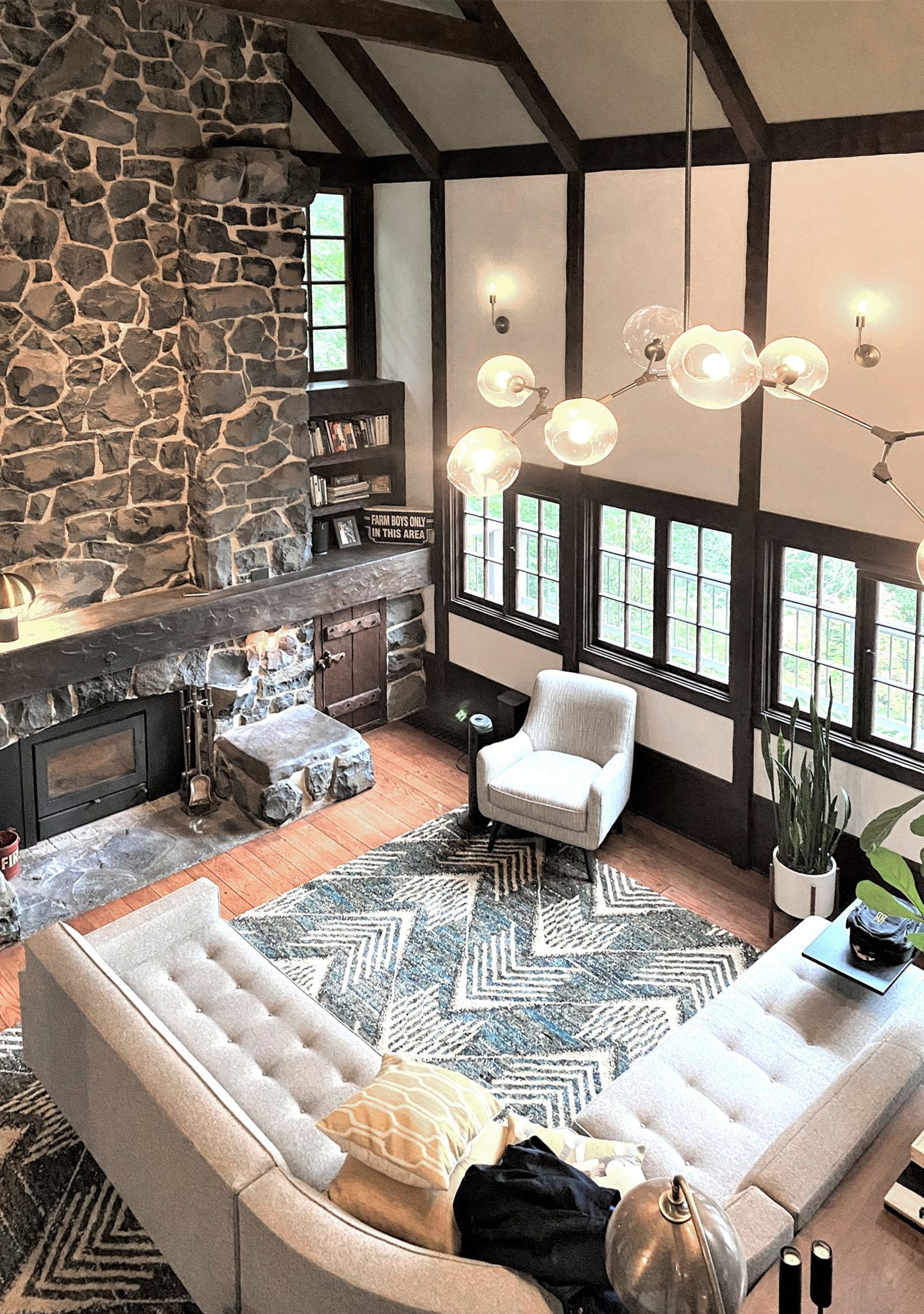 Looking down at the original living with its full height fireplace, high ceiling and bank of original casement windows in this 1932 Tudor