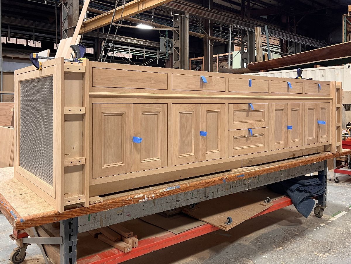 A large, period-inspired island for a Dunthorpe neighborhood kitchen under construction in the Arciform cabinet shop. The metal grilles at either end will hide radiators traditional radiators. 