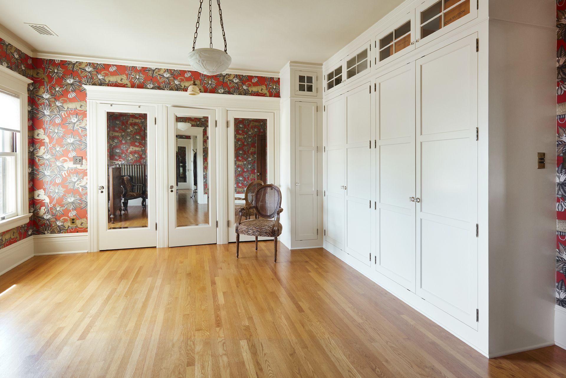 An underused bedroom was turned into a wallpapered dressing room with a wall of custom full height painted cabinets.