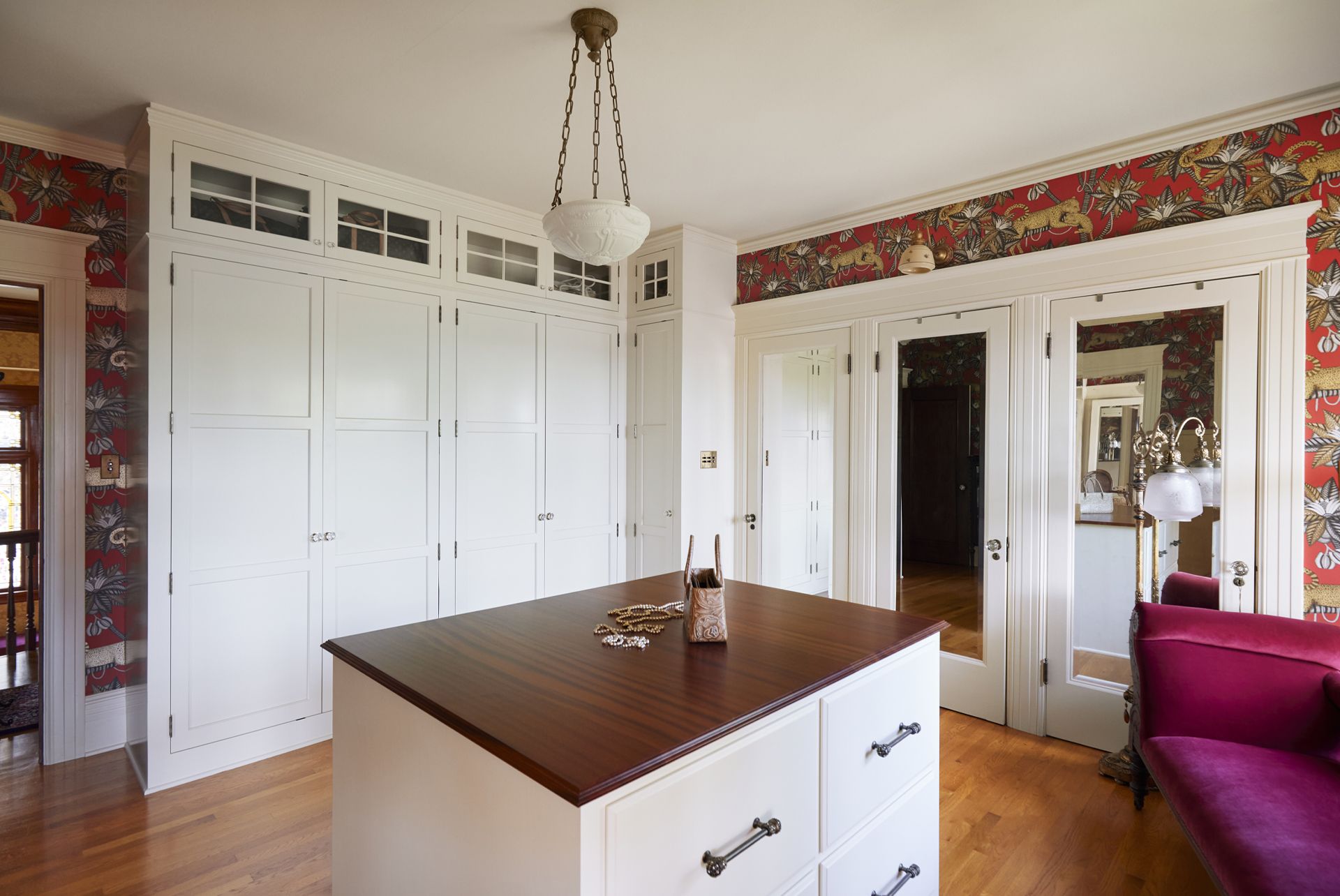 Another dressing room has a central island, full height cabinets and a door to a shoe library.