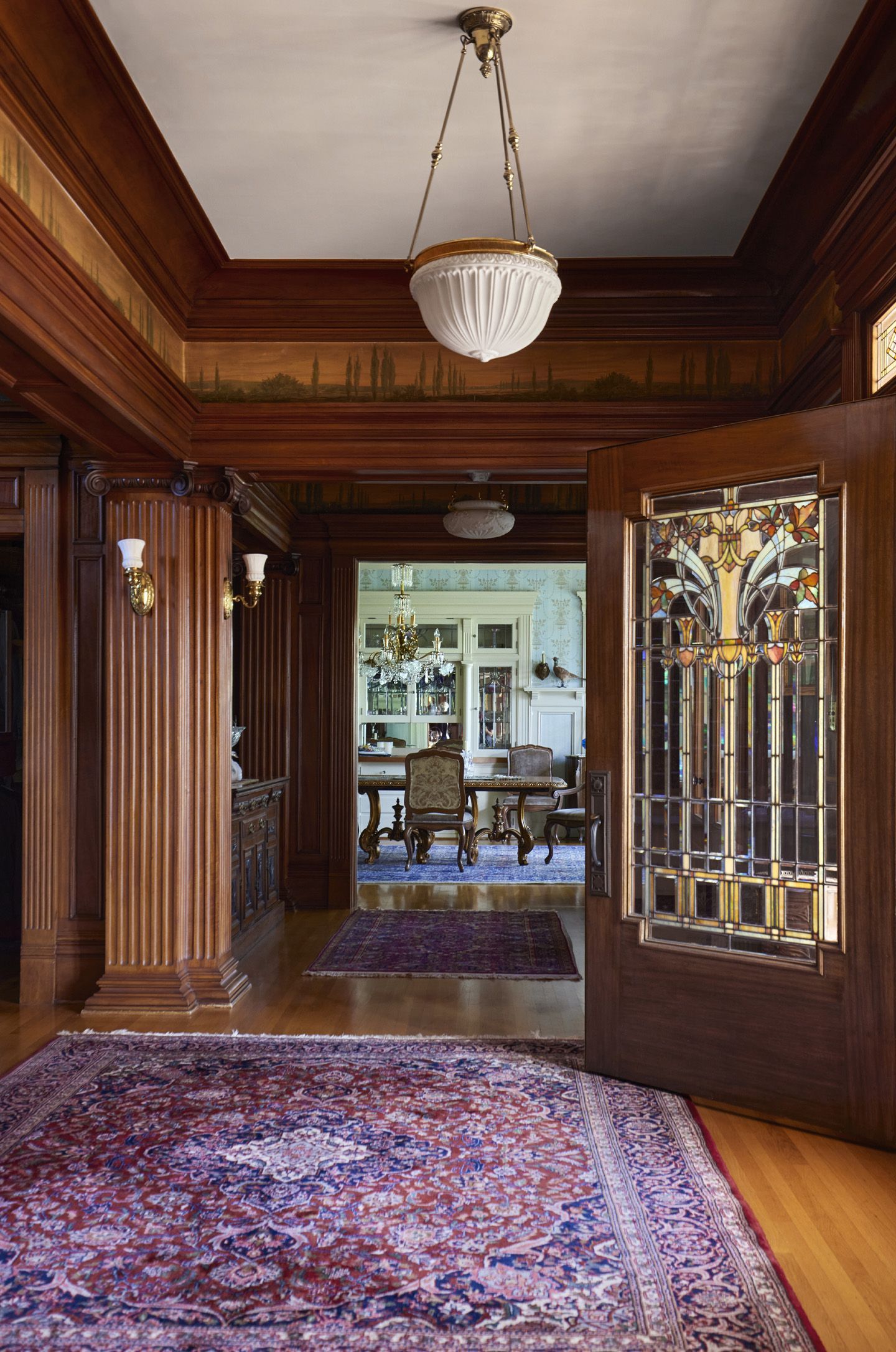At the base of the main staircase is a generous entry, with original frieze, leaded glass door and mahogany millwork.