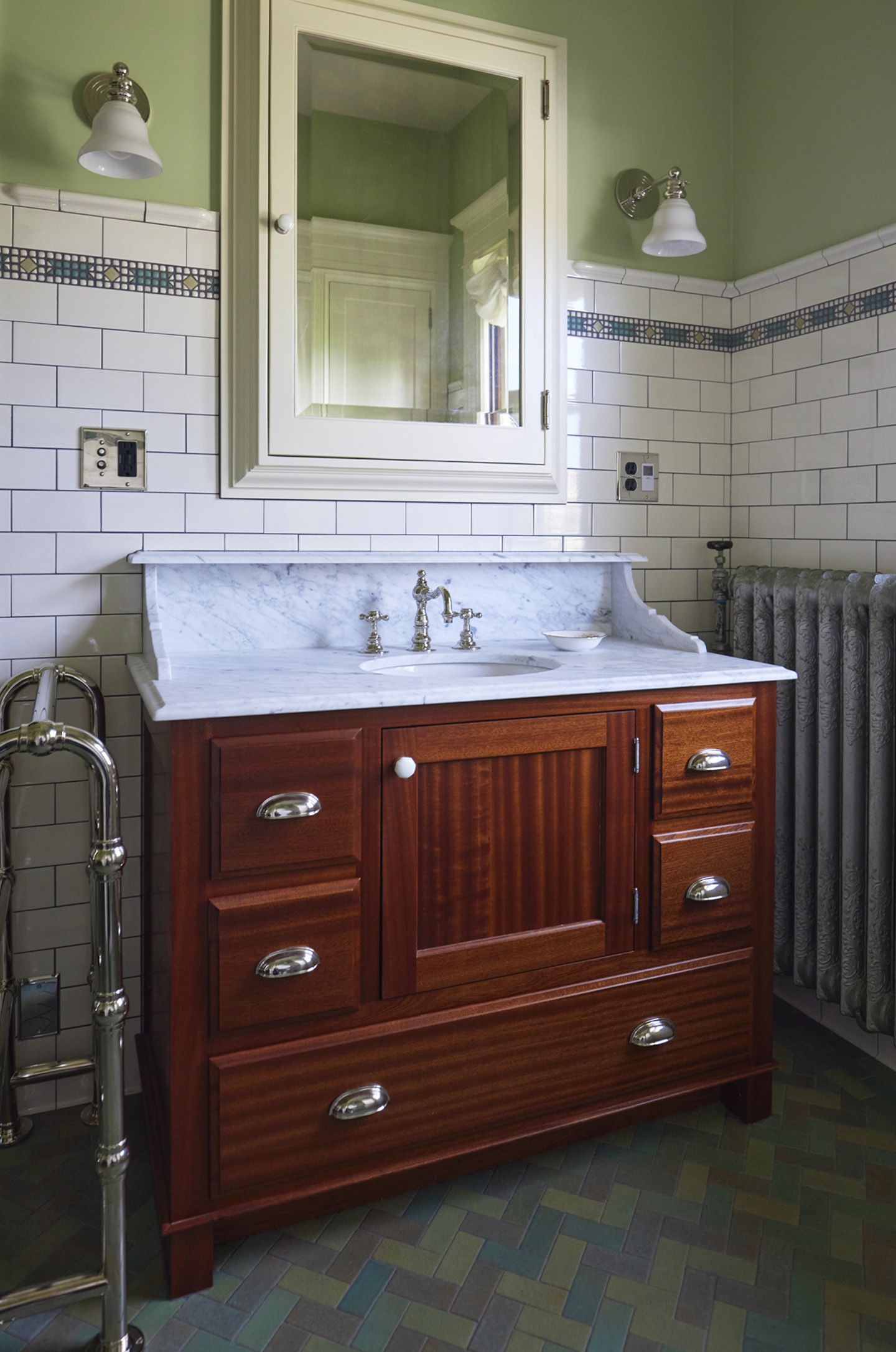 The mahogany vanity sits between the towel warmer and the original radiator and is topped with marble with aa built in shelf under the medicine cabinet.
