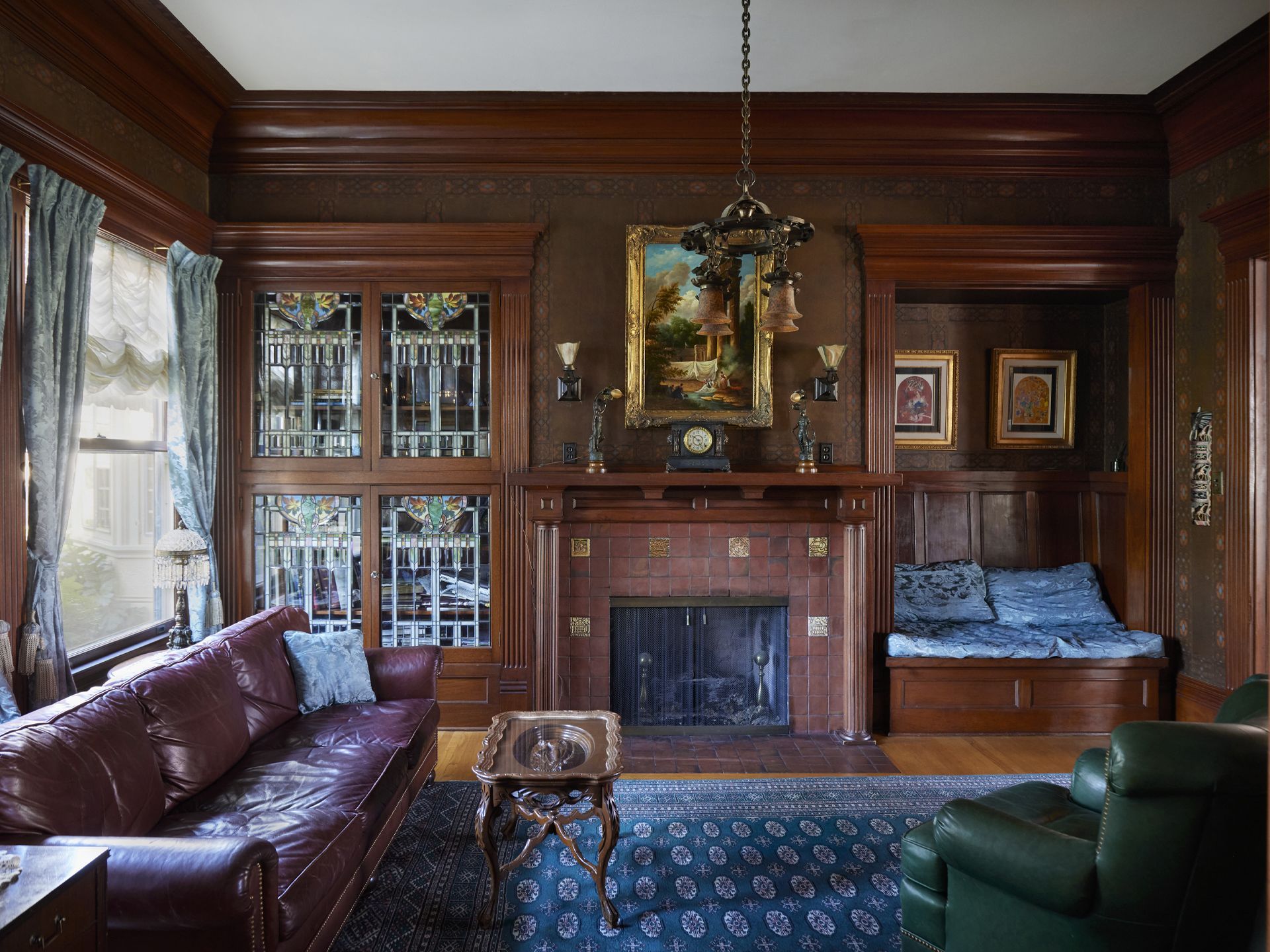 Adjacent to the living room and entry is the library, with cozy seating, stained glass window to the rear and at the built in cabinet, and tile-faced fireplace.