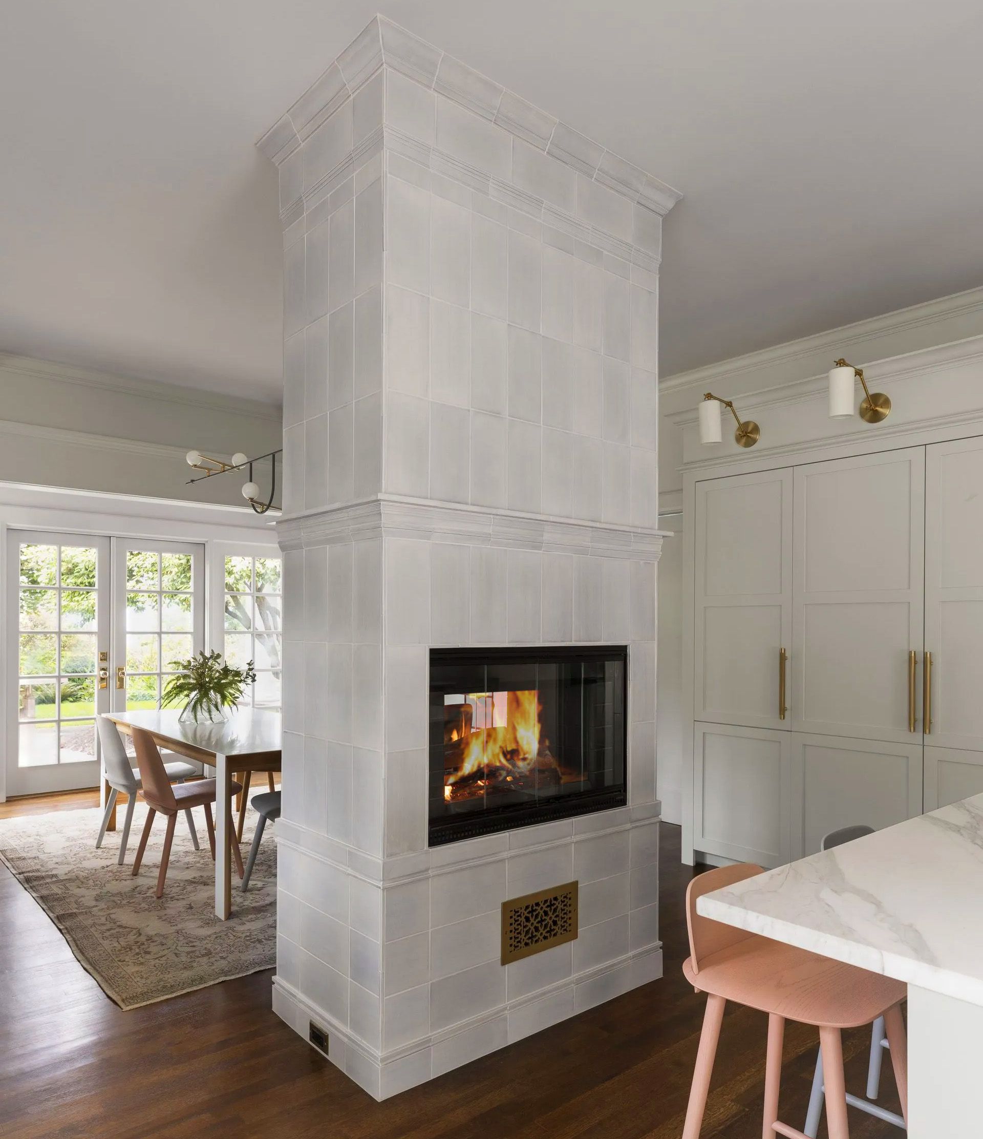 Standing tall in the middle of the connected kitchen and breakfast room, the double-sided fireplace is based on a European kachelofen (tiled stove). 