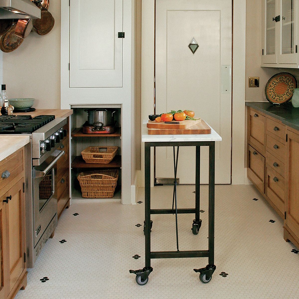 For this craftsman-style galley kitchen a marble top rolling cart provides a handy work surface for cutting and prepping mid-way between sink and stove. 