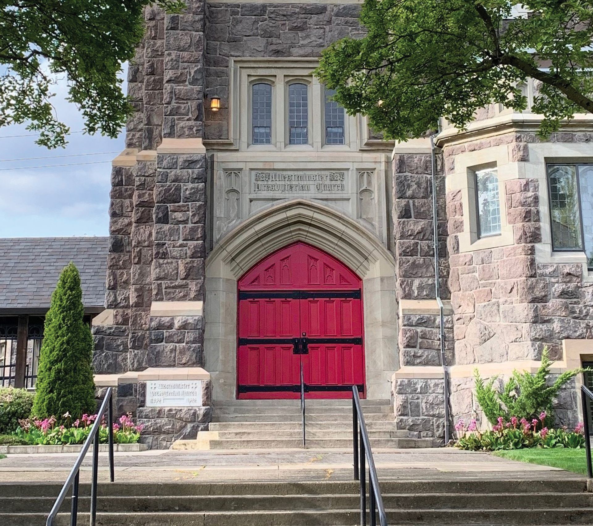 A brick building with a red door and stairs